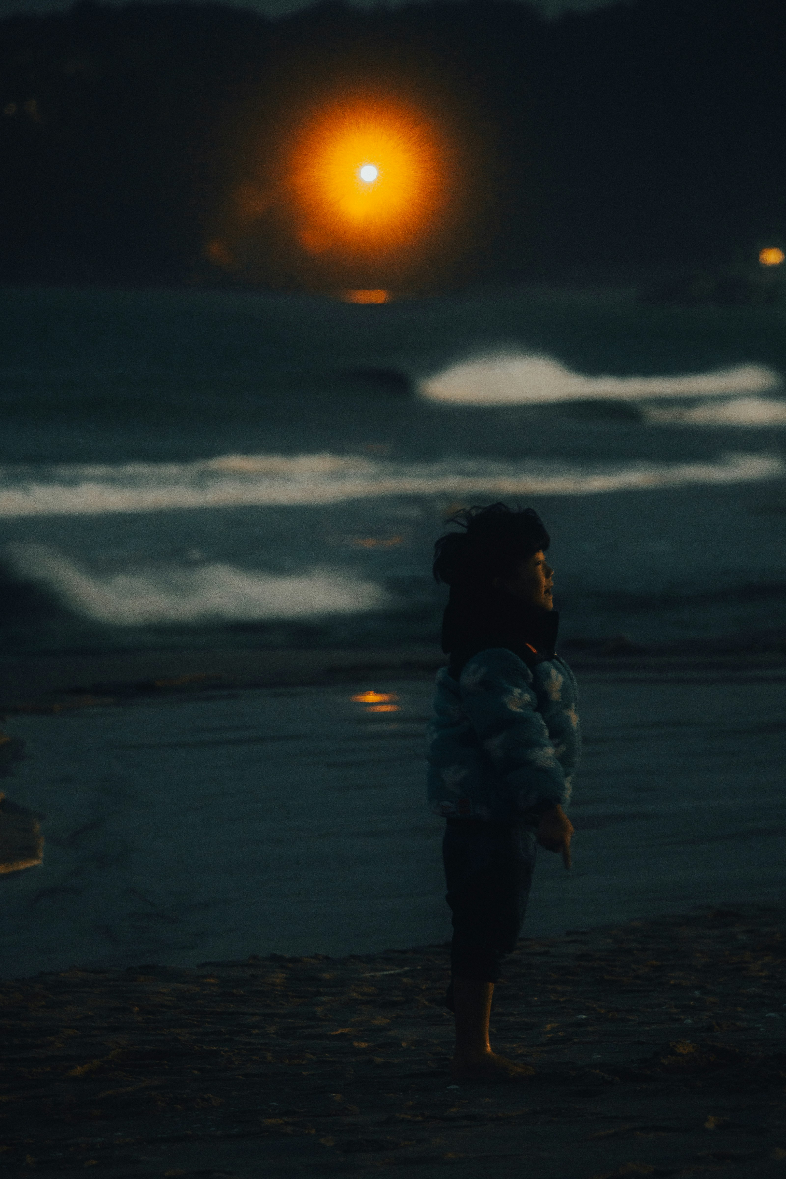 夕暮れの海辺を歩く人影のある砂浜