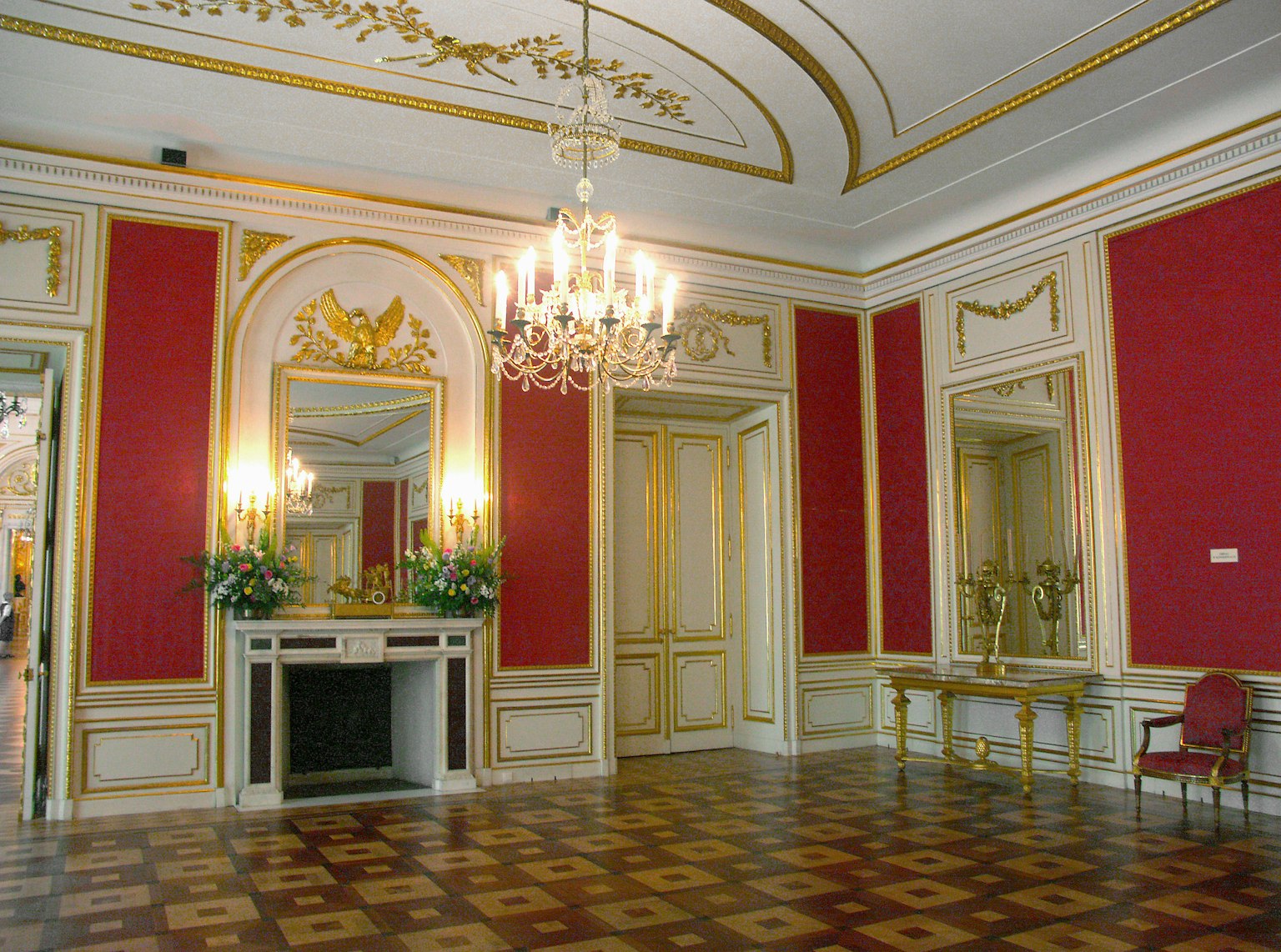 Eleganter Raum mit reichhaltiger Dekoration mit einem Kronleuchter roten Wänden und goldenen Akzenten