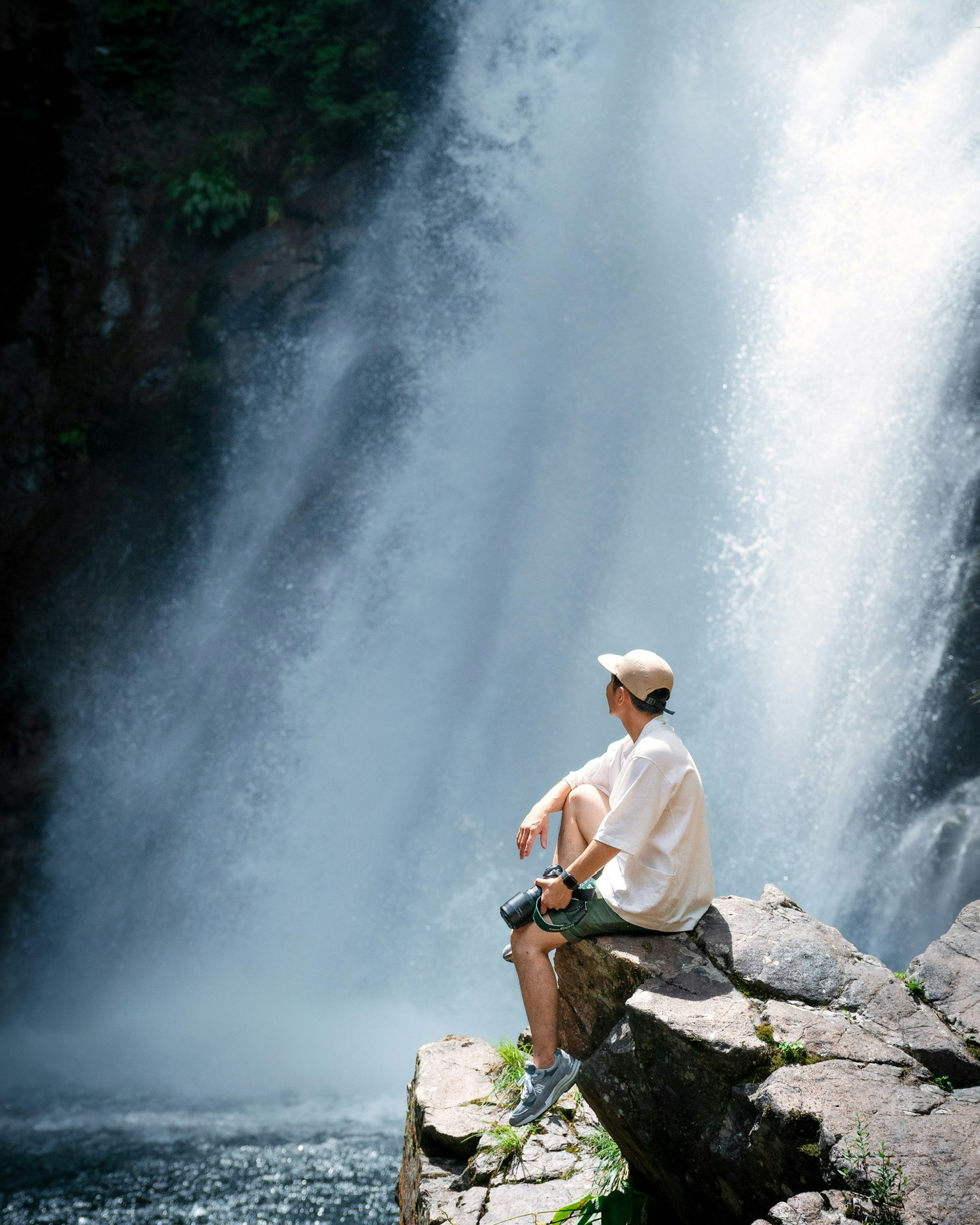 Un hombre sentado en una roca cerca de una cascada disfrutando de la belleza de la naturaleza