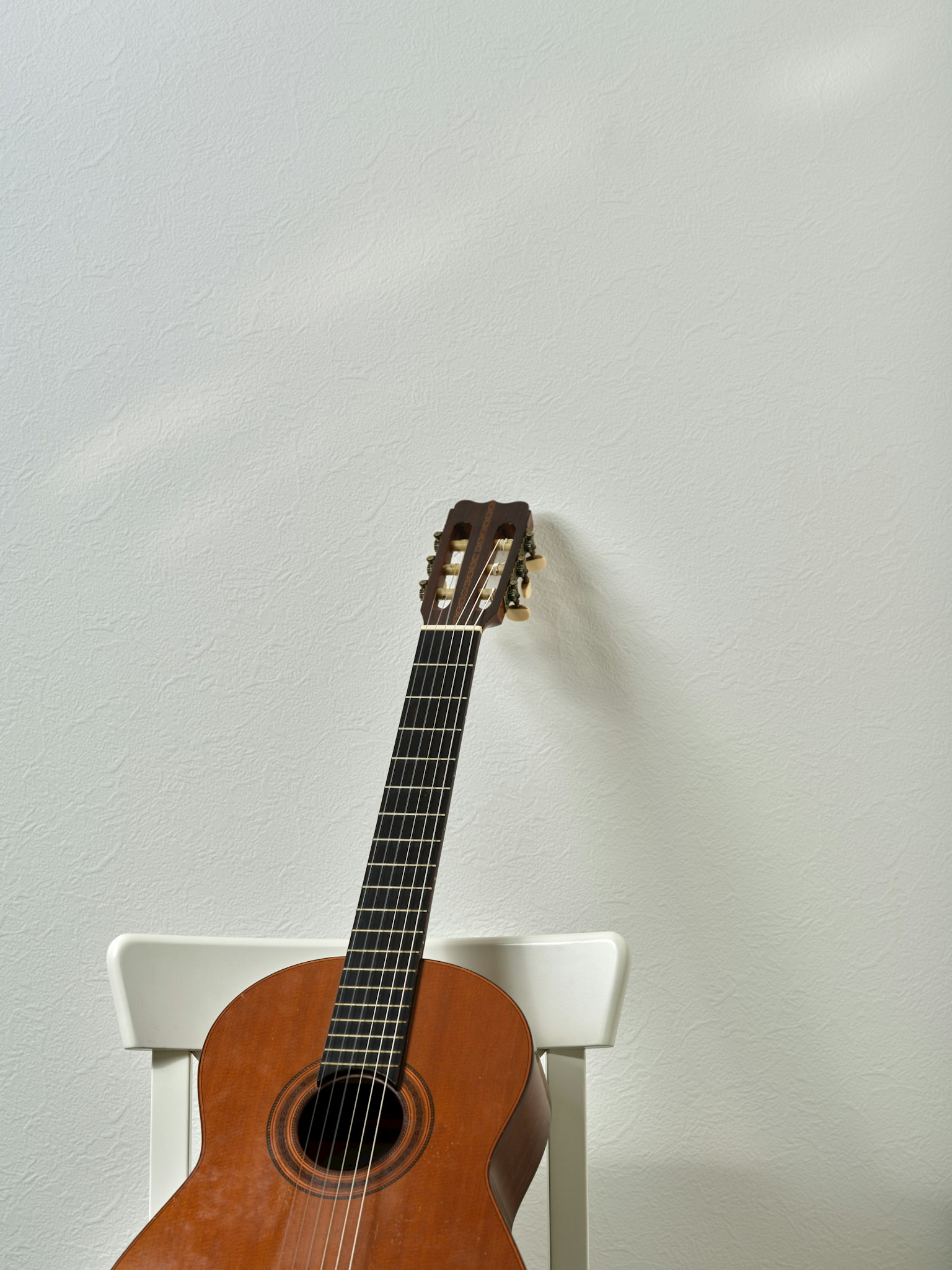 靠在白色牆壁上的木吉他