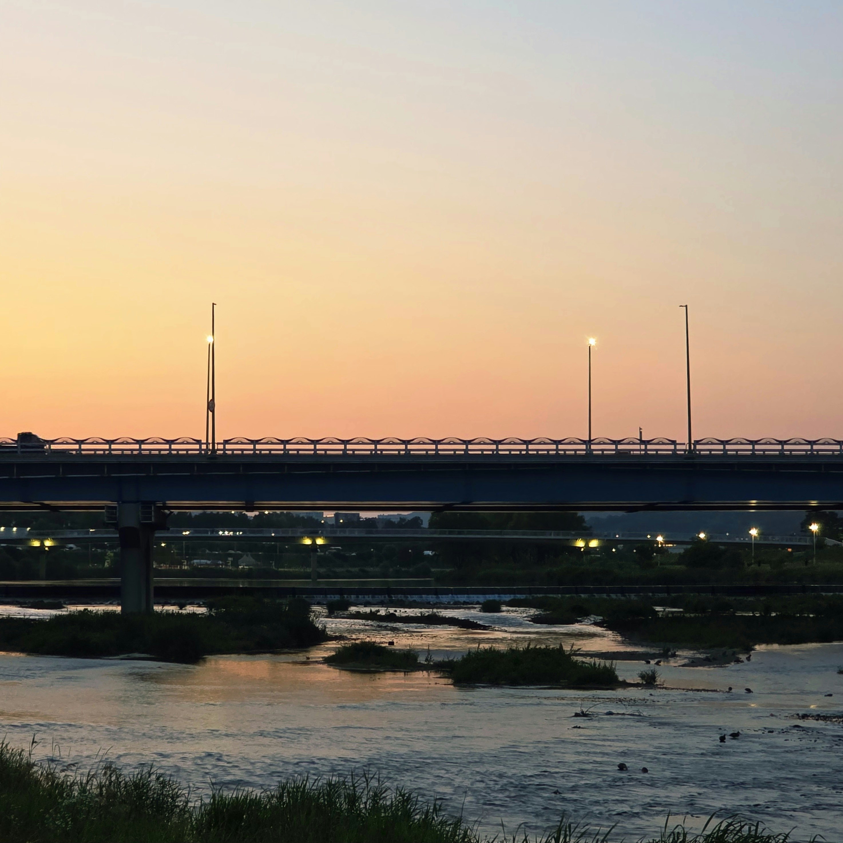 夕暮れの川沿いを走る橋と街灯のある風景