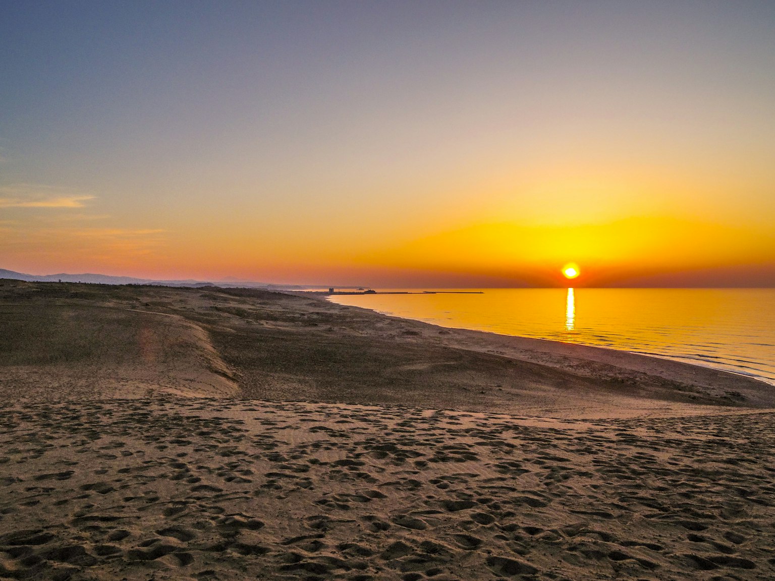 Sore yang indah di atas laut tenang dengan pantai pasir dan ombak lembut