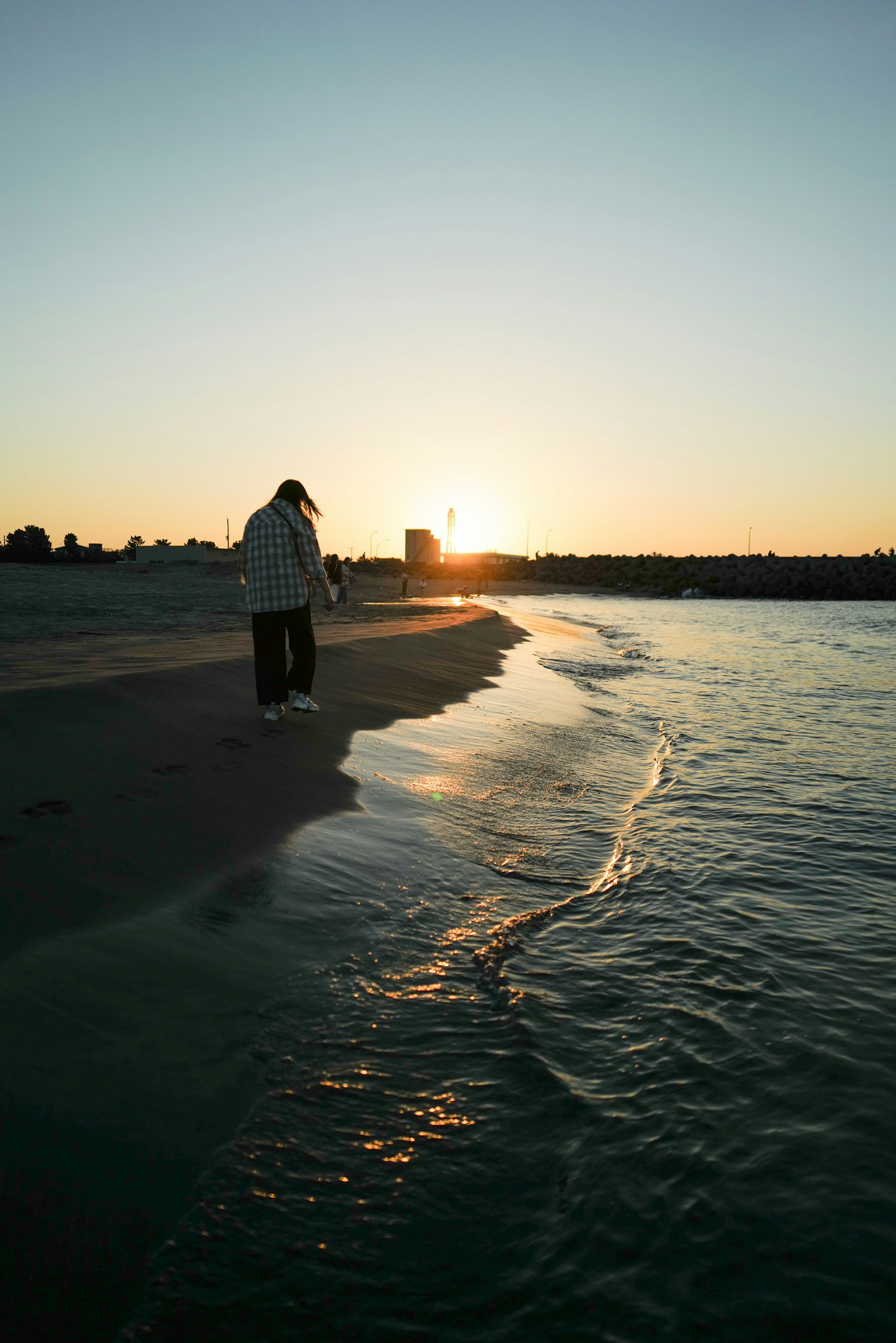 คนเดินอยู่ริมหาดในขณะที่พระอาทิตย์ตก