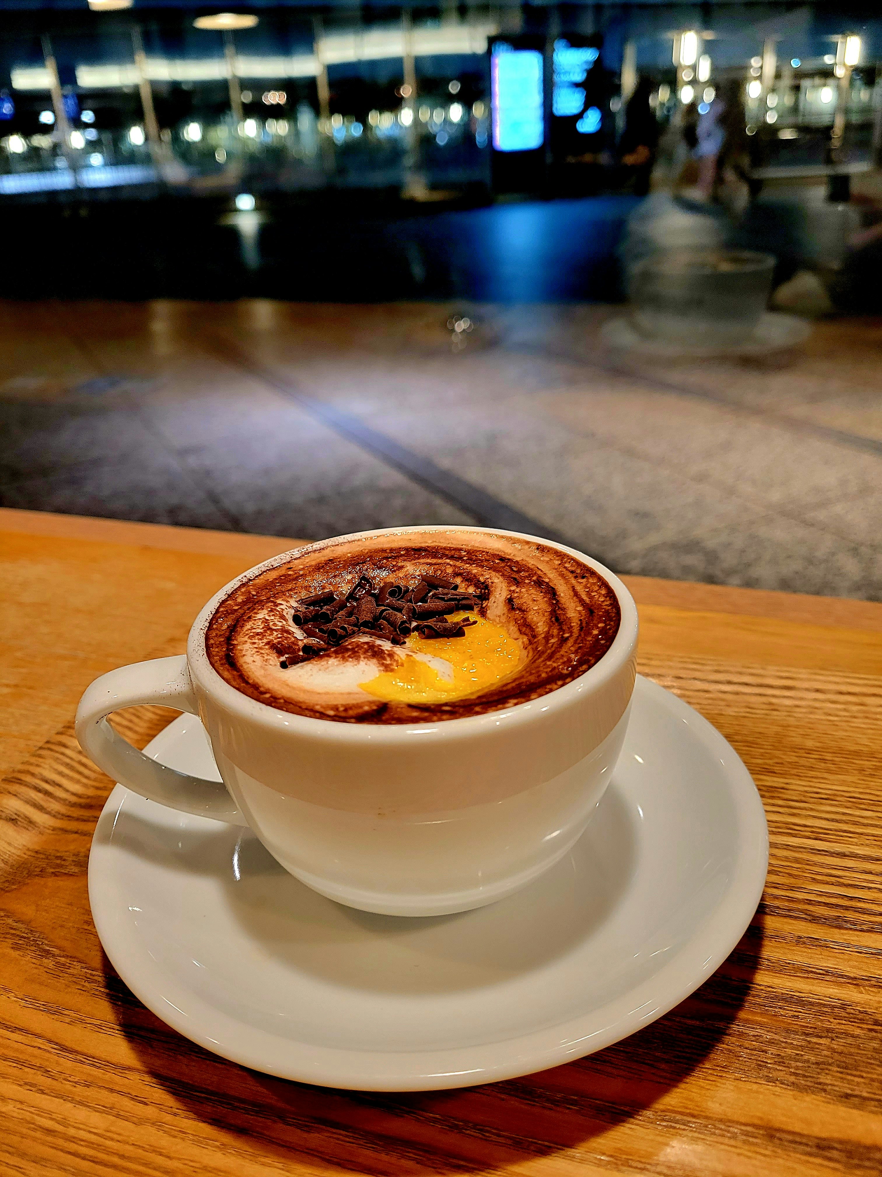 木のテーブルに置かれたラテアートのカフェラテ画像