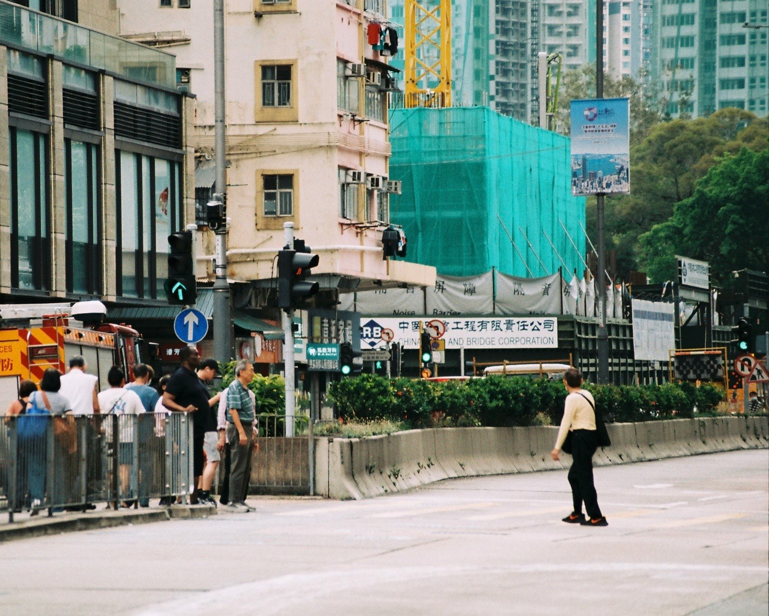 urban intersection sidewalk with construction fencing and people walking