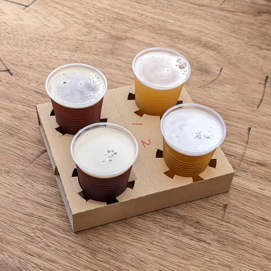 ensemble de dégustation de bière dans des gobelets en papier sur une table en bois