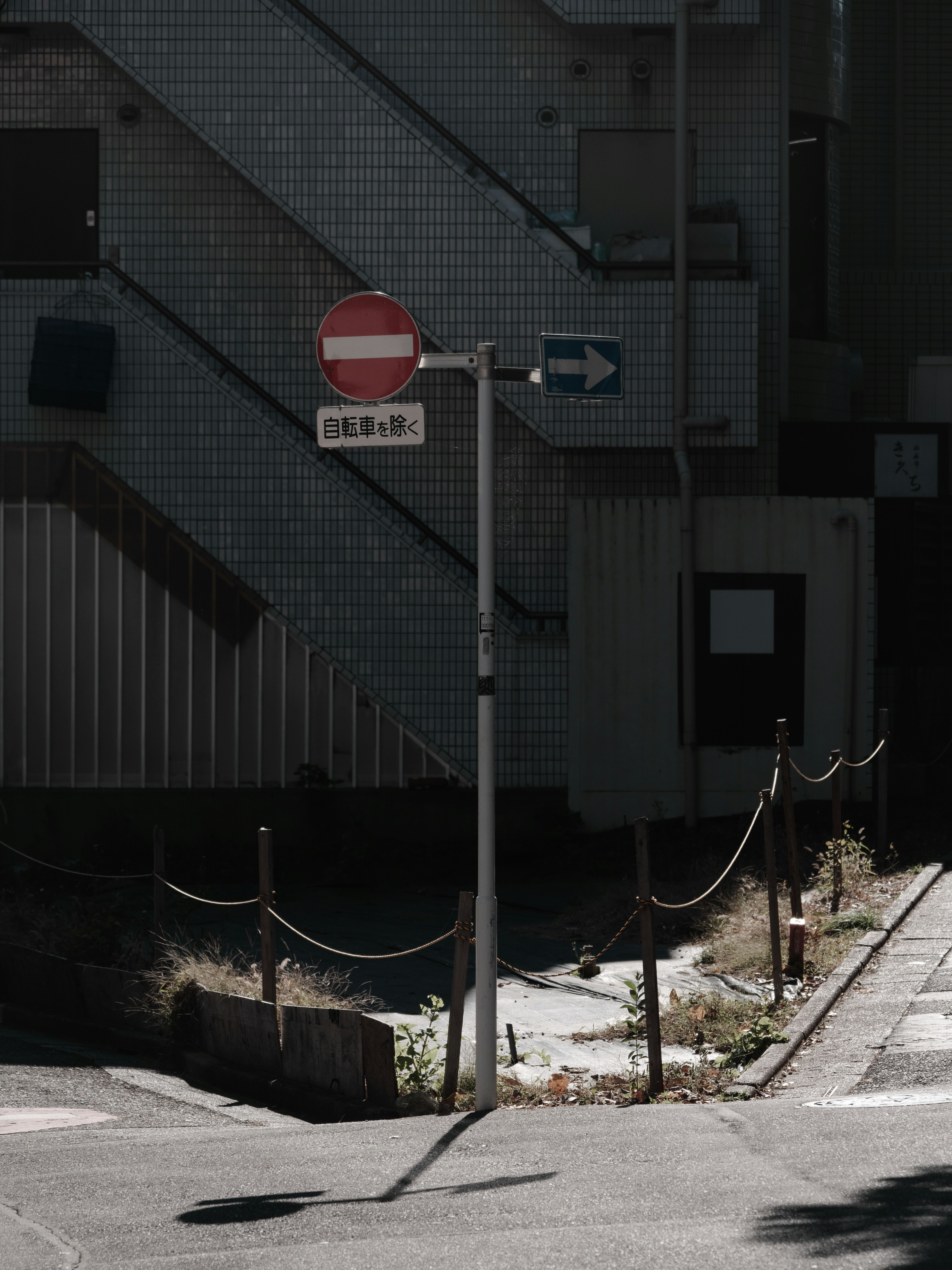 階段のある路地での一方通行標識とロープ柵