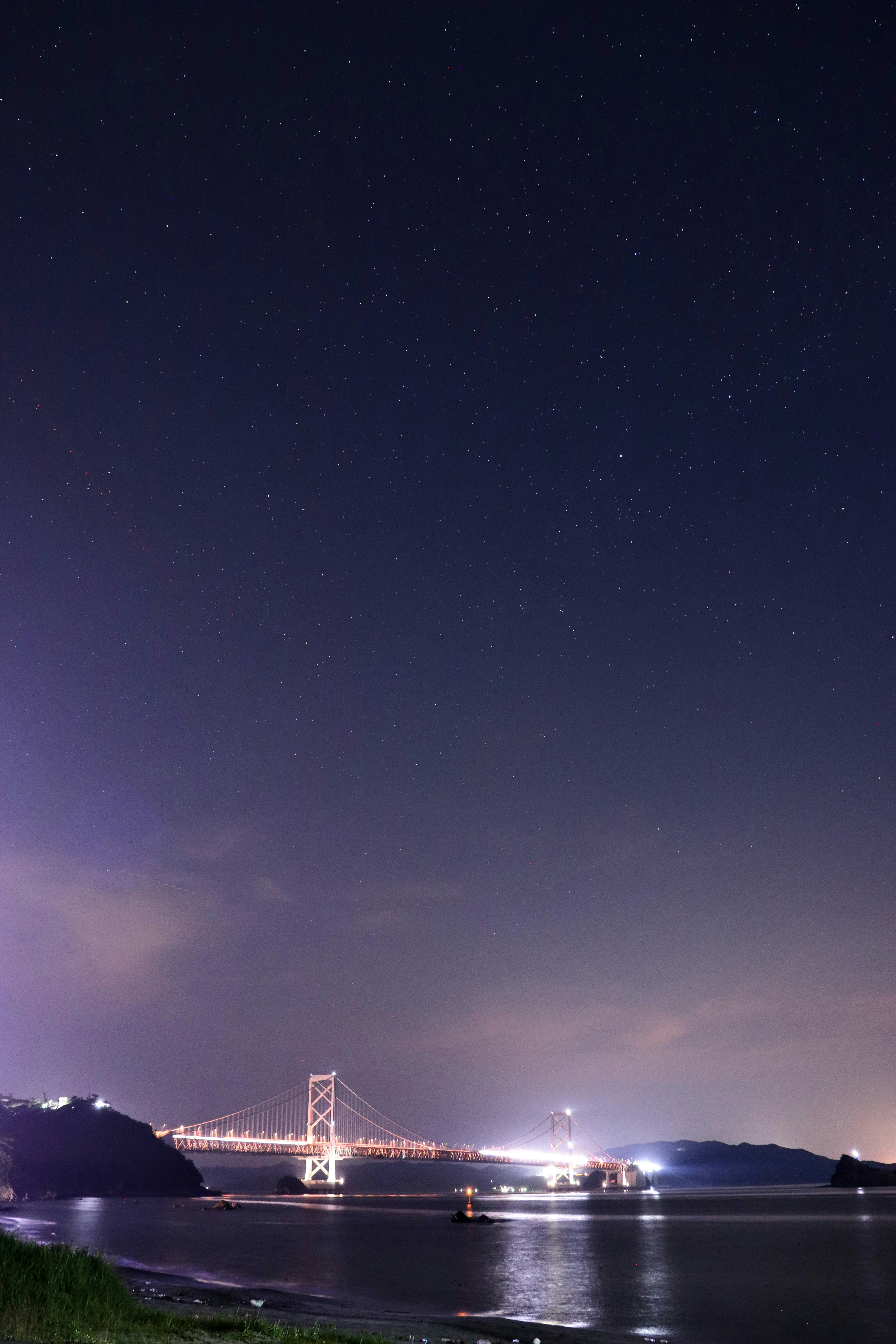 星空の下の海上に浮かぶ橋の夜景