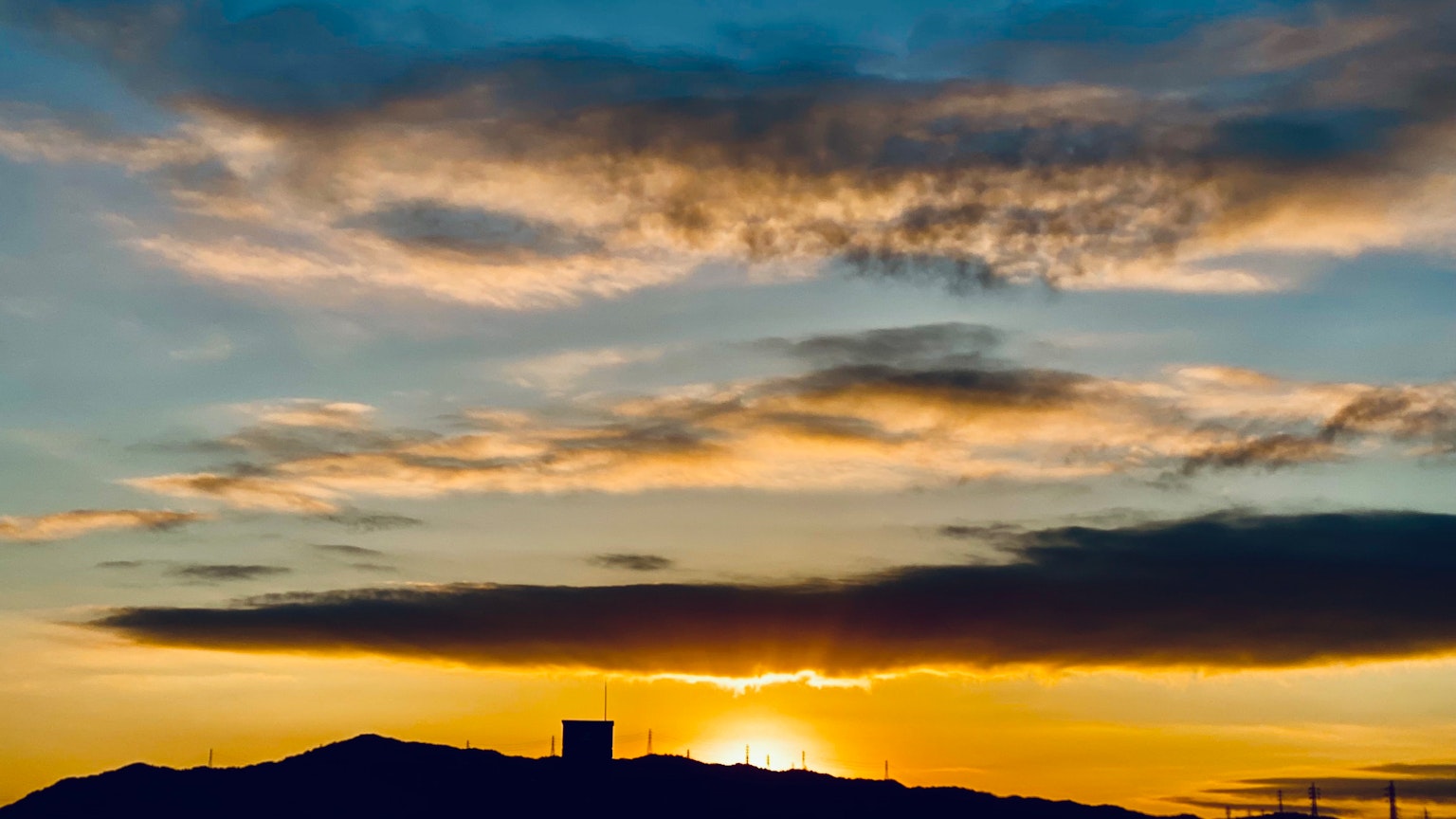 Bellissimo paesaggio con il sole che tramonta dietro le montagne e le nuvole