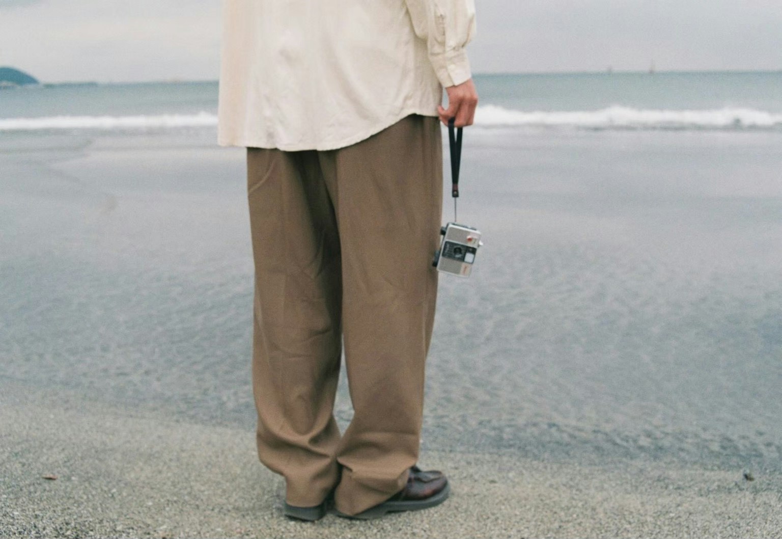 站在海邊的男人手持相機