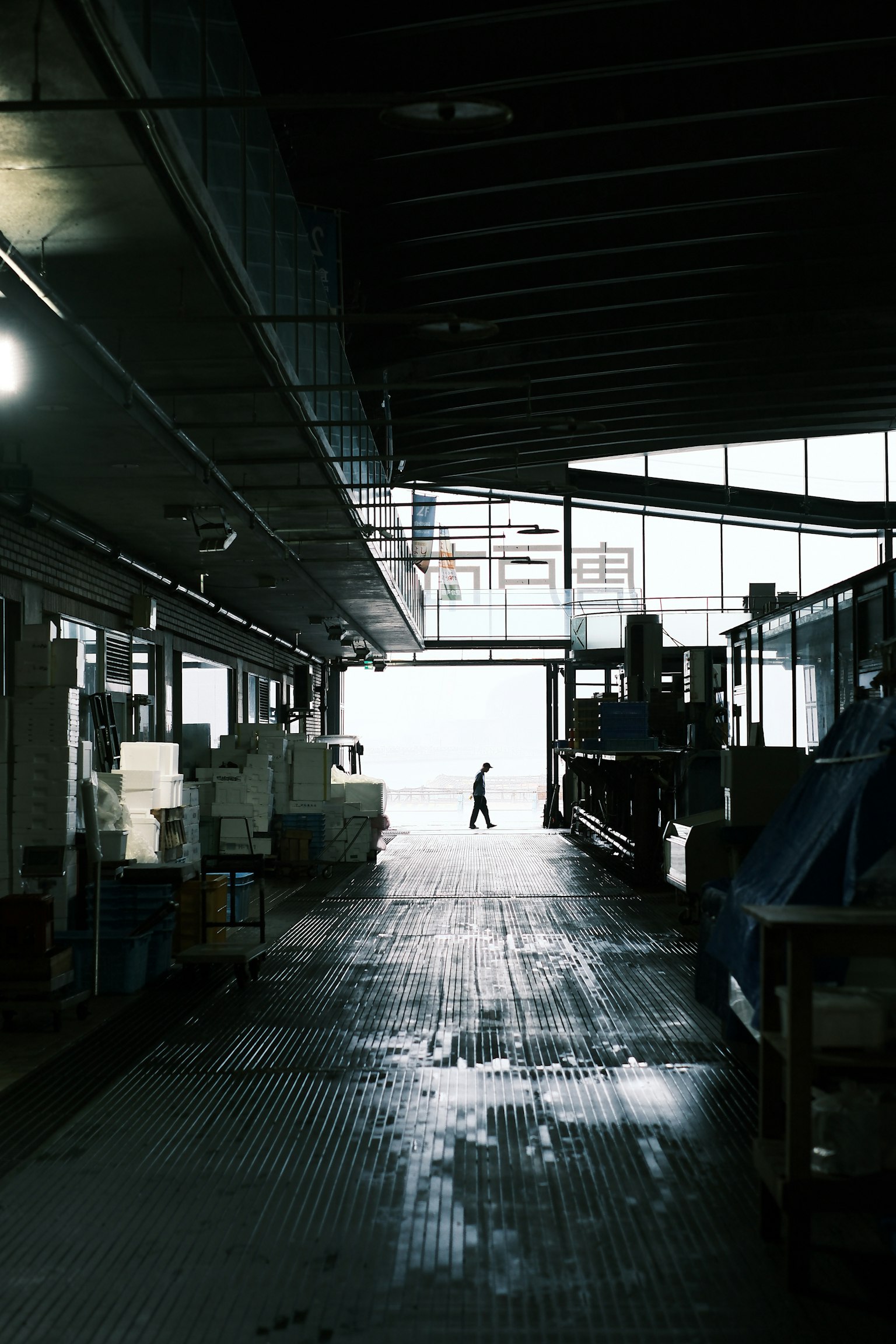 Silueta de una persona en un espacio industrial pasillo oscuro que lleva a una salida brillante