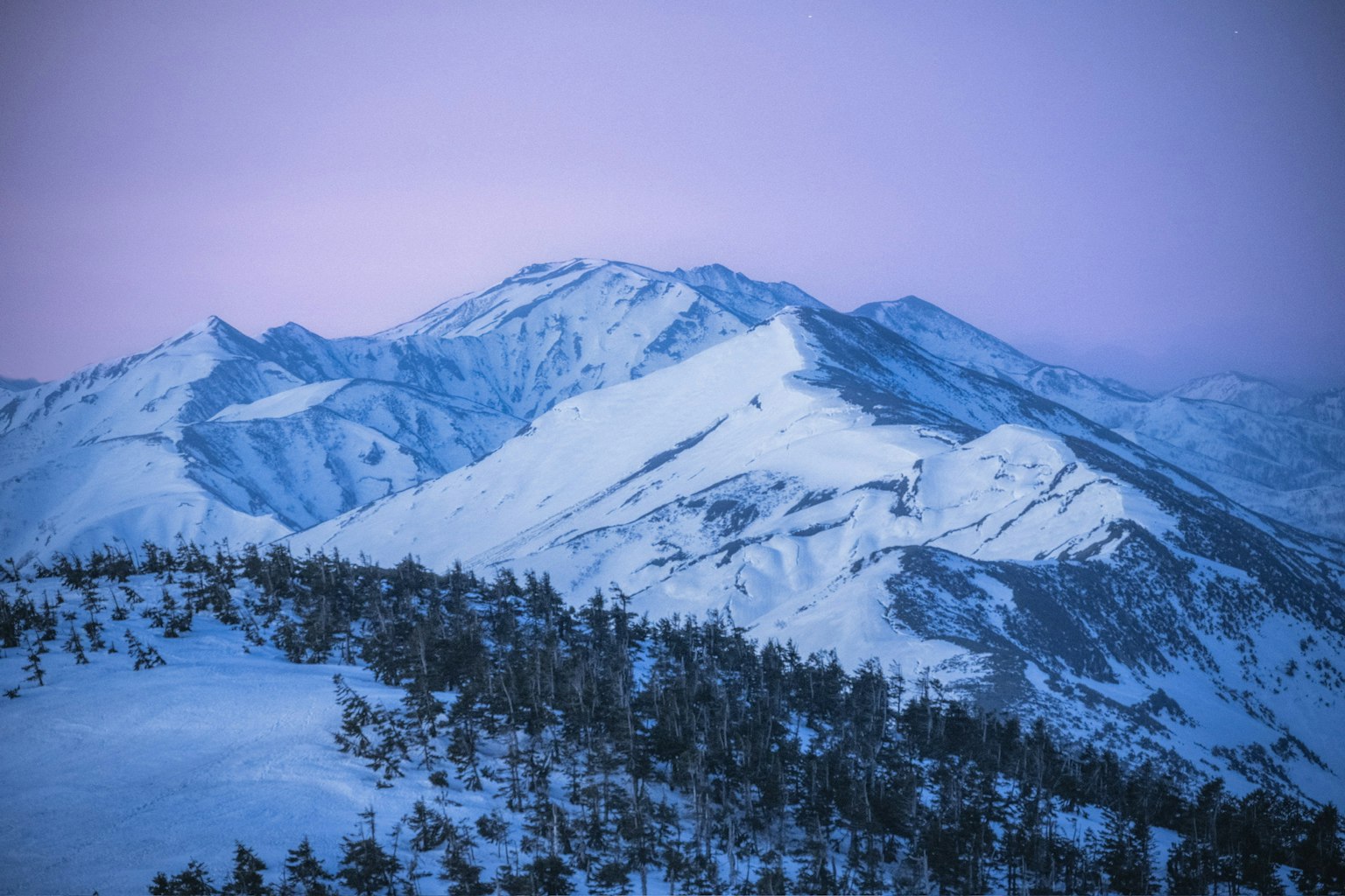 Snow-covered mountains under a purple sky