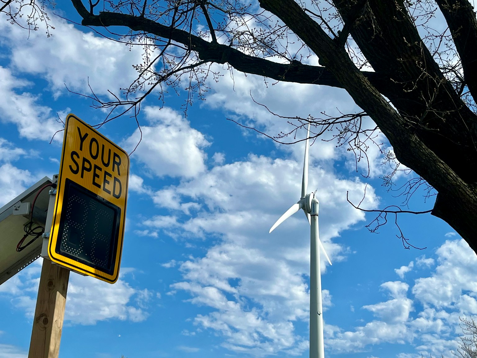 Speed display sign under blue sky with wind turbine