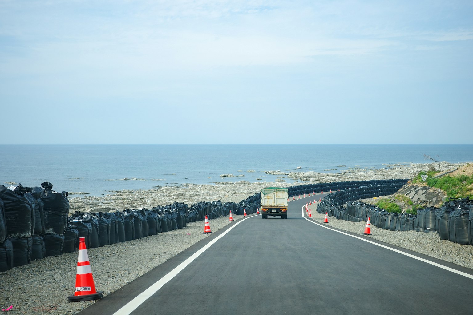 Scenic coastal road with black protective barriers and ocean view