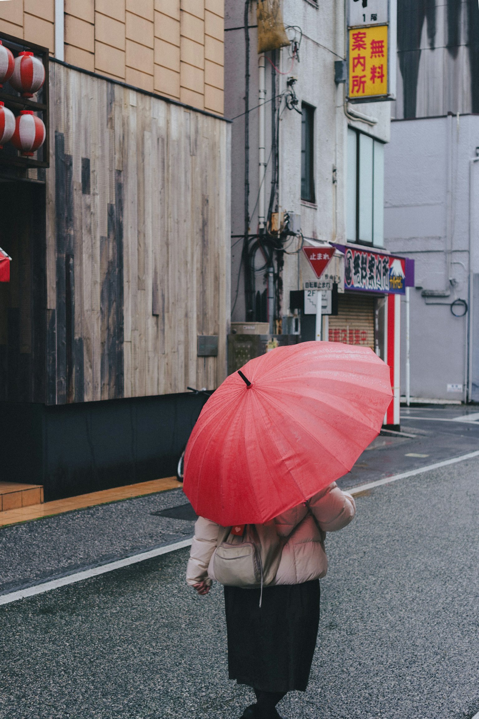 Một người phụ nữ đang đi trên phố cầm một chiếc ô đỏ