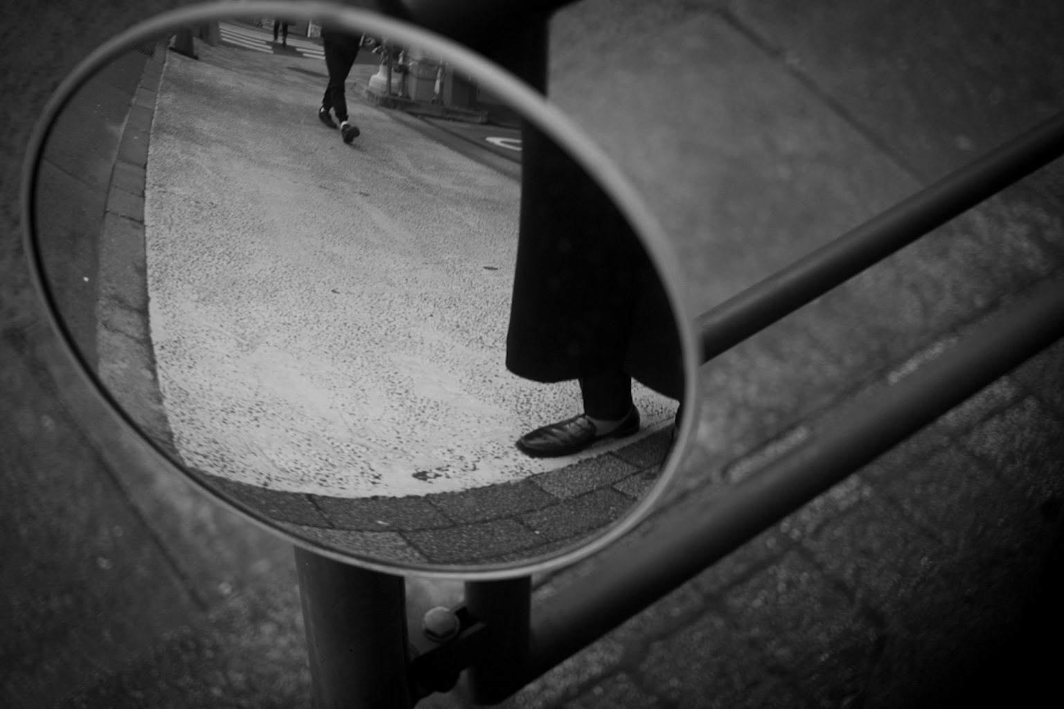 黒と白の反射の中に映る足と歩道