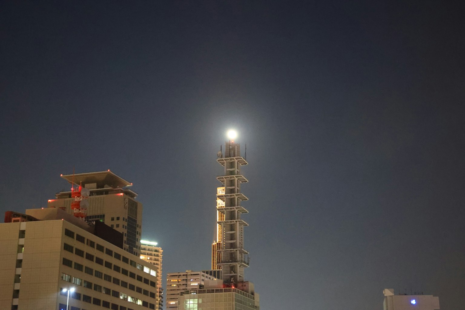 A tower illuminated by the bright moon against a night sky
