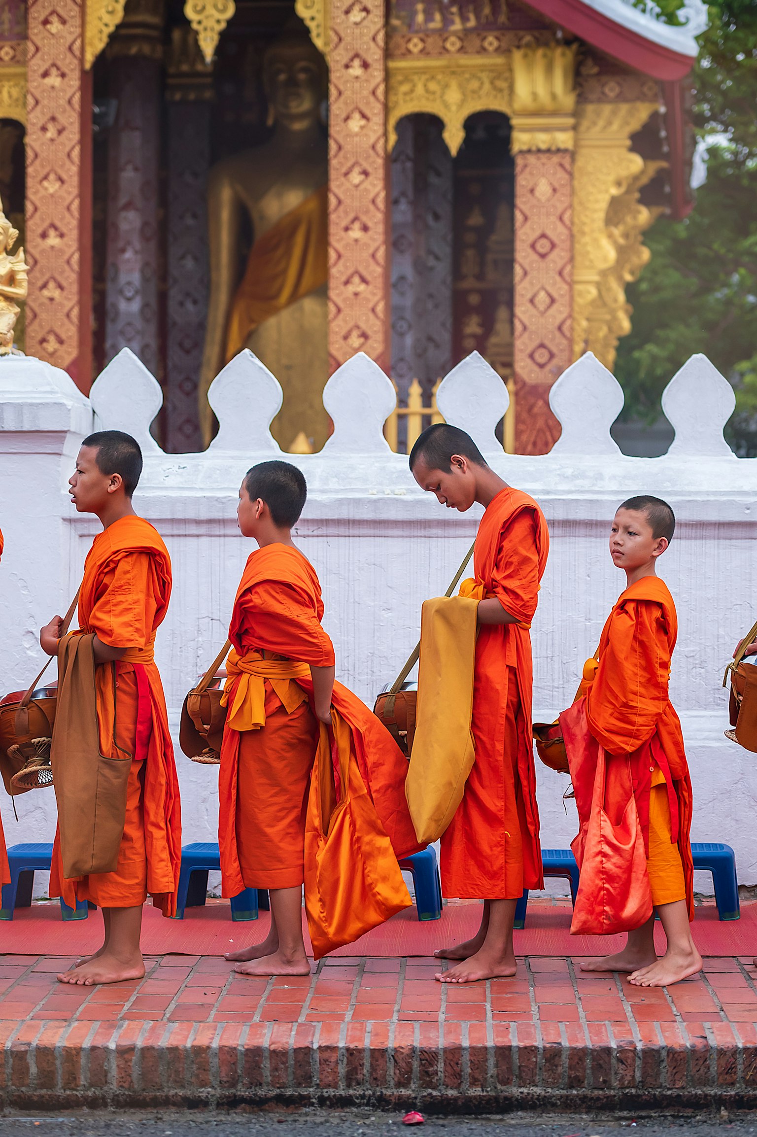 Junge Mönche in orangefarbenen Roben, die vor einem Tempel gehen