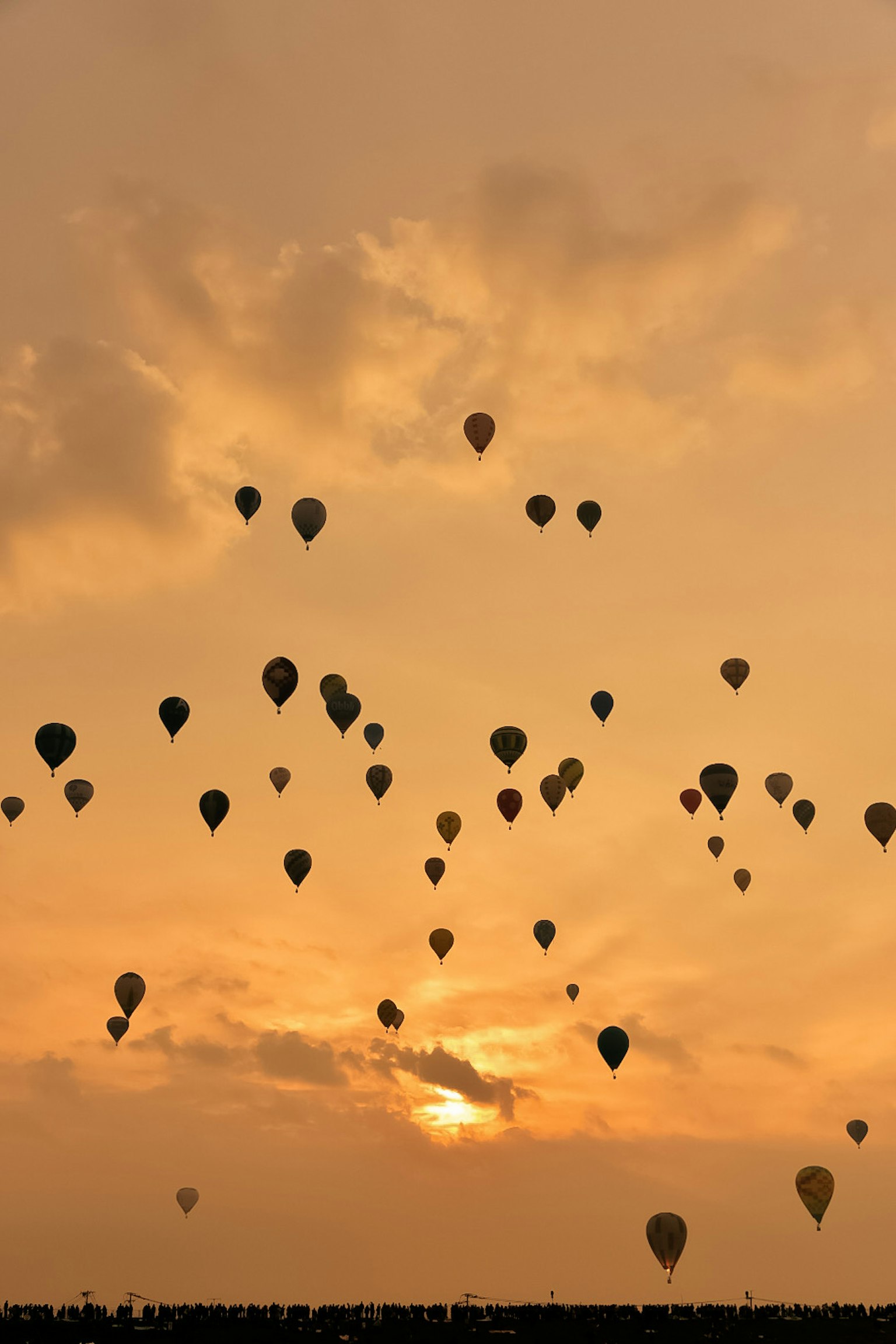 De nombreux montgolfières flottant dans un ciel au coucher du soleil