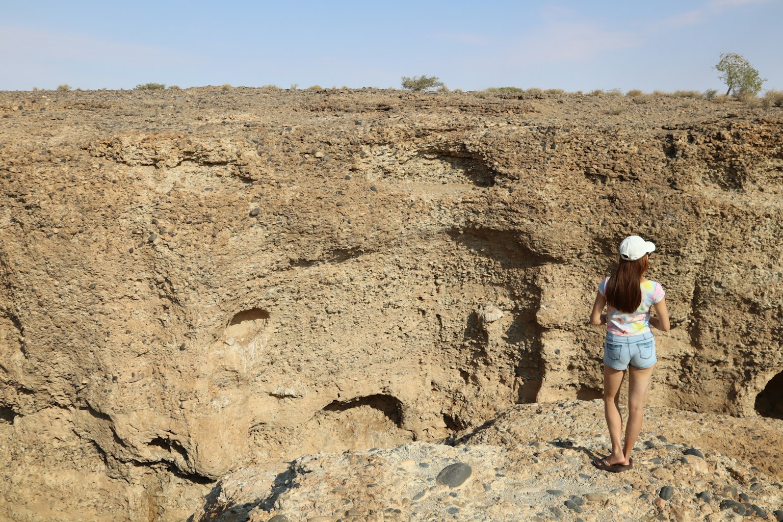 Eine Frau steht am Rand einer Klippe und blickt auf eine trockene Landschaft