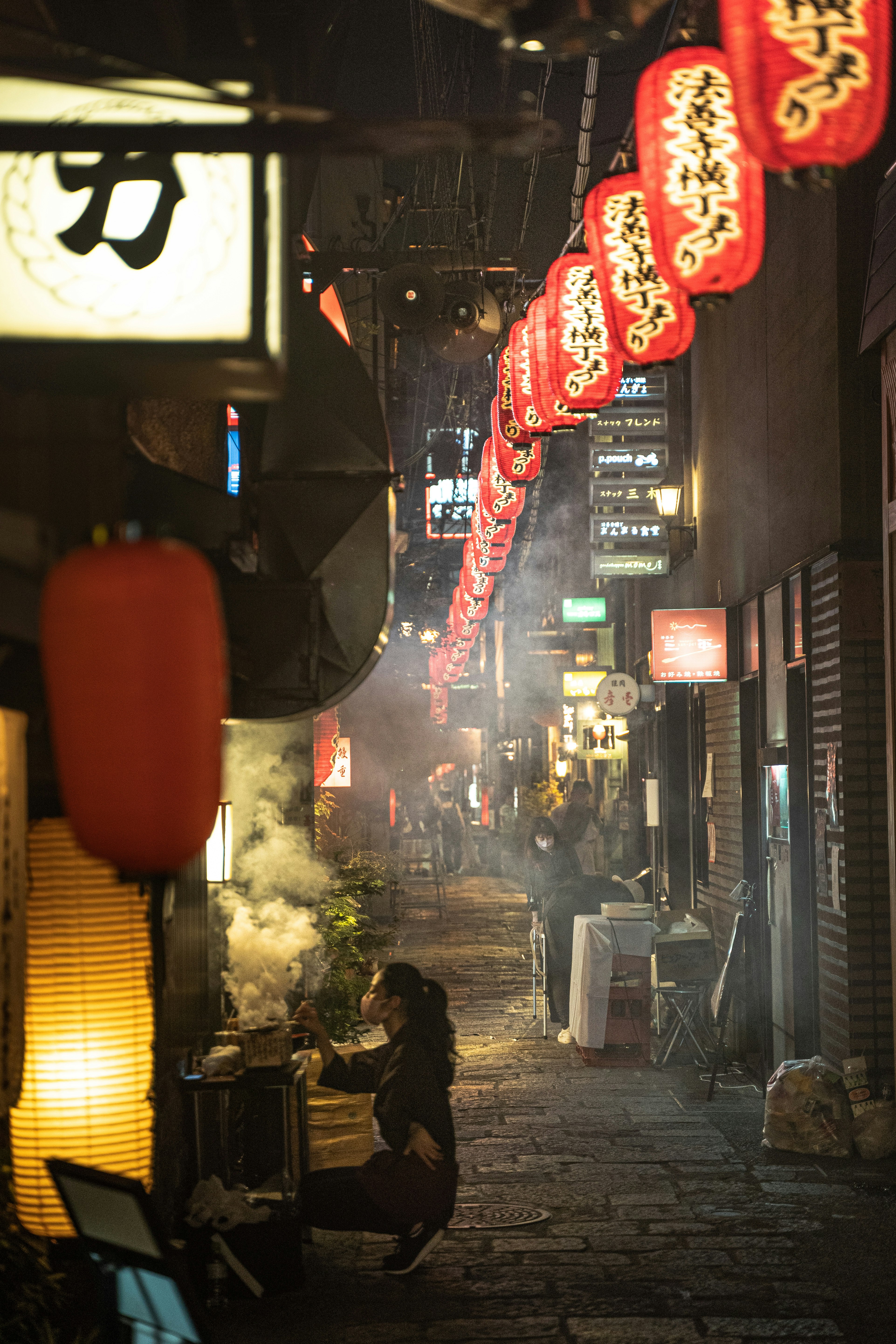 路地の提灯と煙が漂う屋台街の夜景