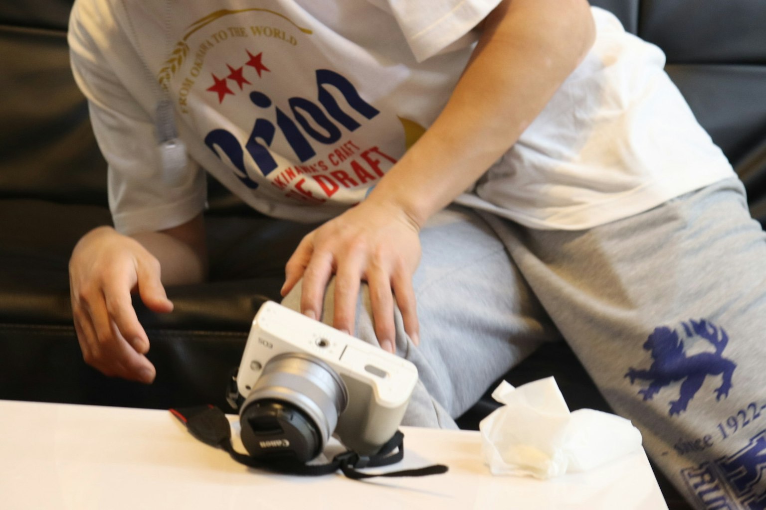 Primo piano di mani che regolano una macchina fotografica bianca su un tavolo