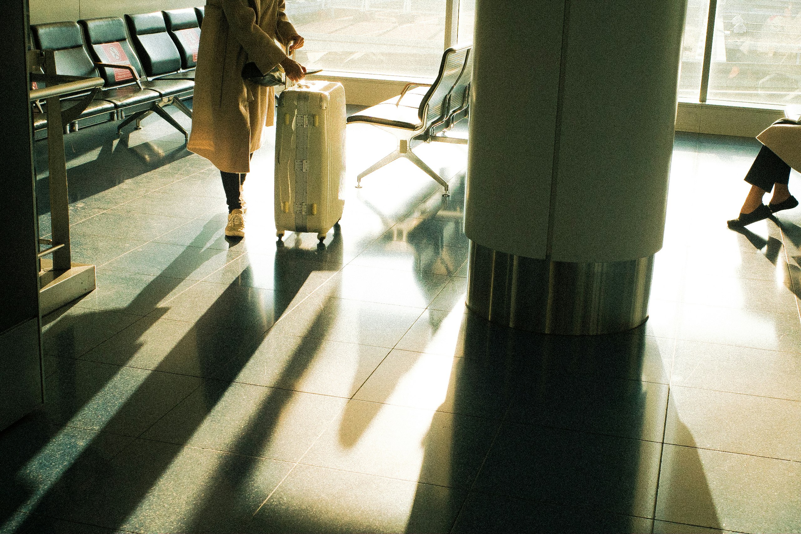 silhouettes of travelers with suitcases in an airport lounge