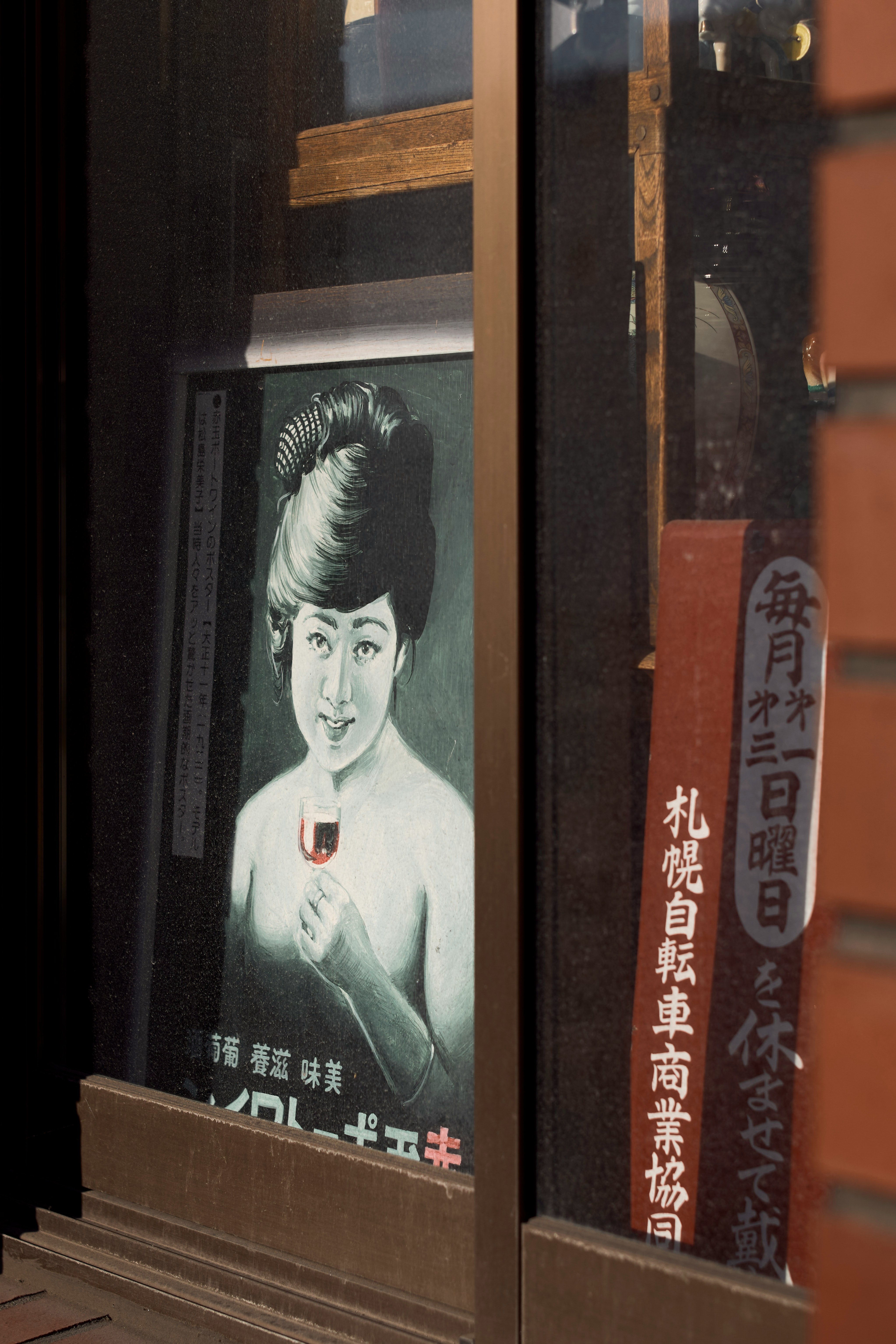 ガラス窓に並ぶレトロな女性ポスターと看板
