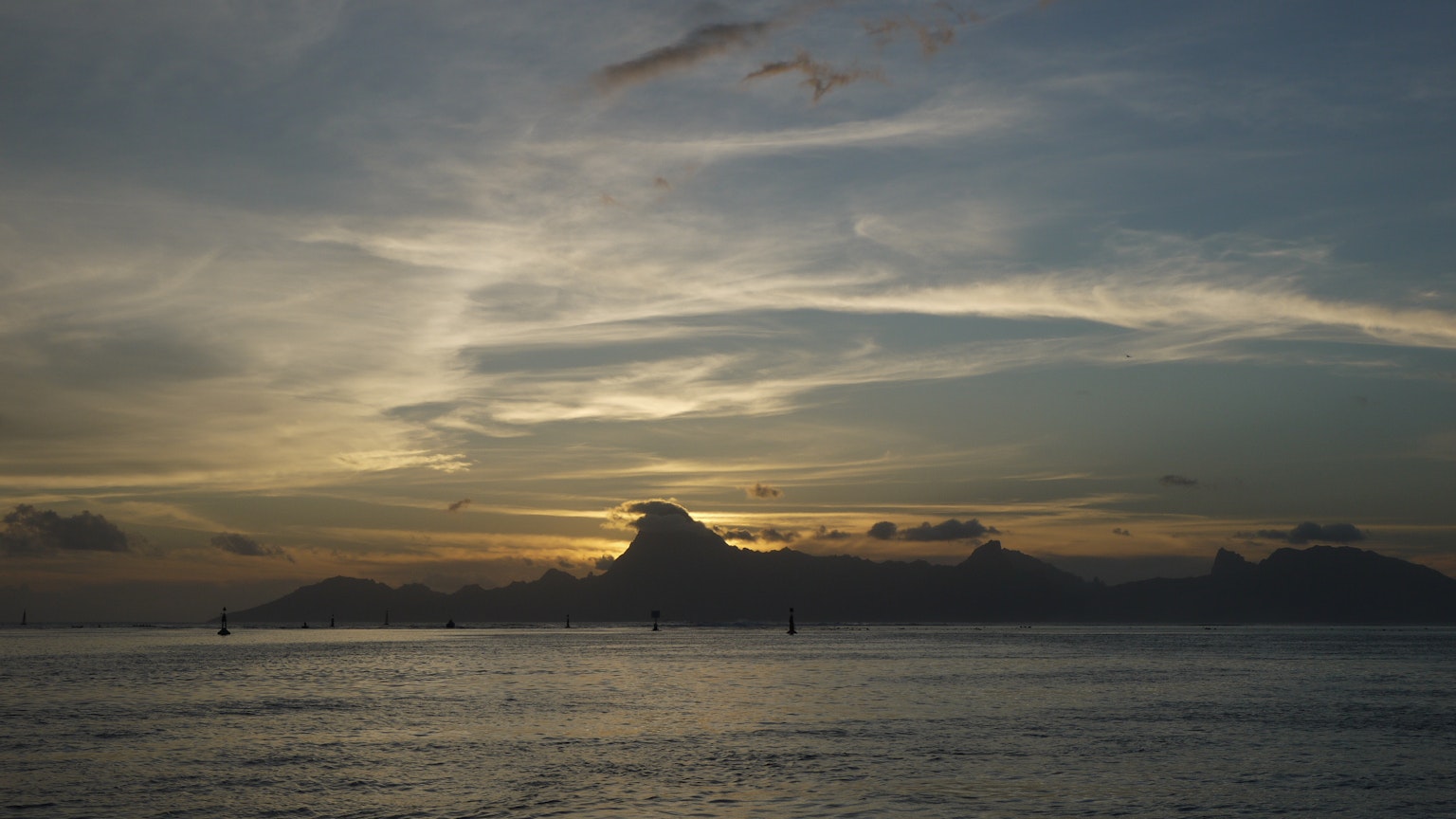 Pemandangan laut saat senja dengan siluet gunung