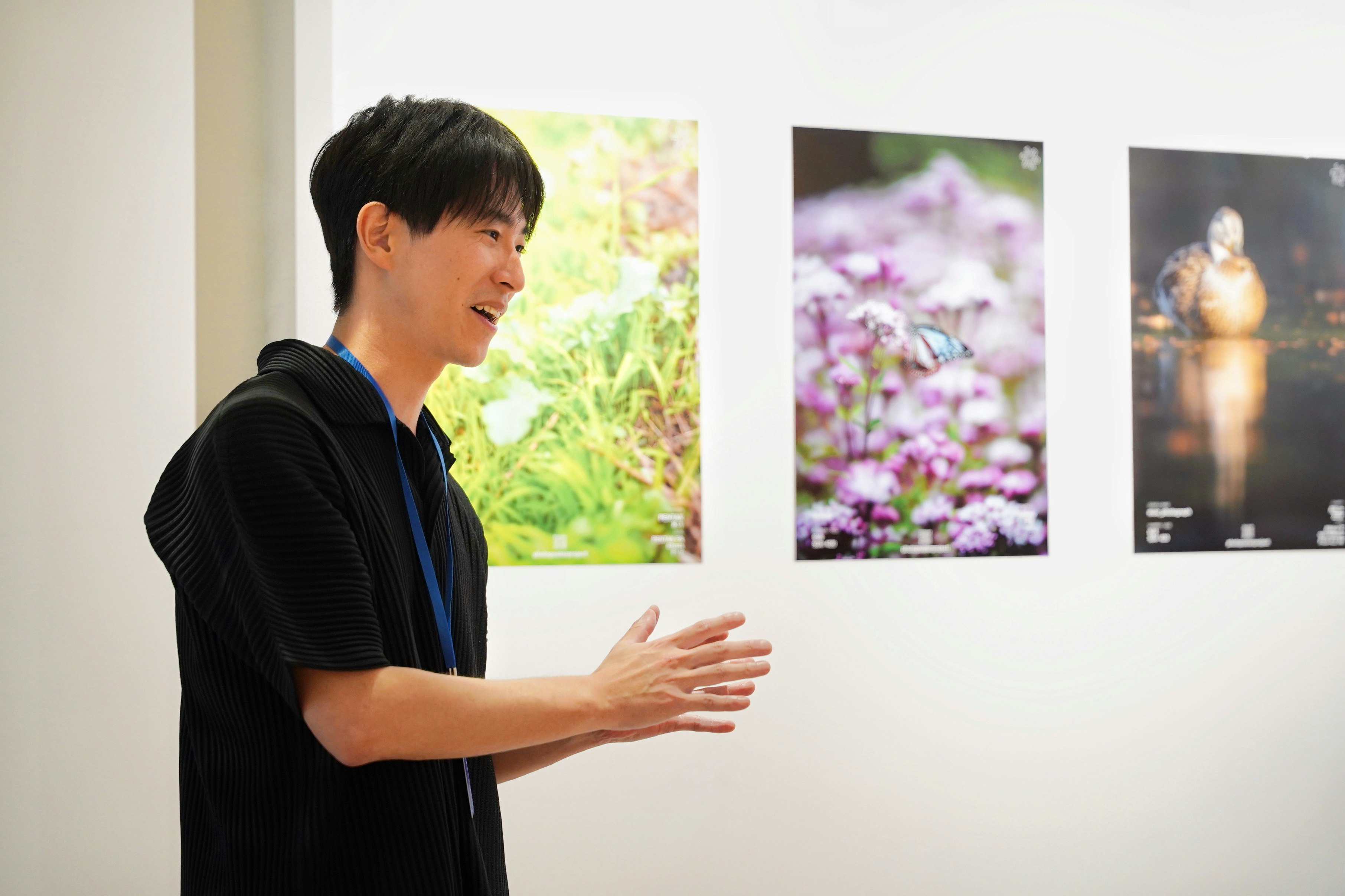 uomo che presenta poster fotografici su una parete di mostra a Kyoto