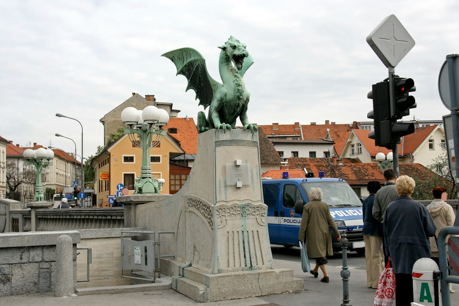 Vista de un puente con una estatua de dragón personas caminando cerca