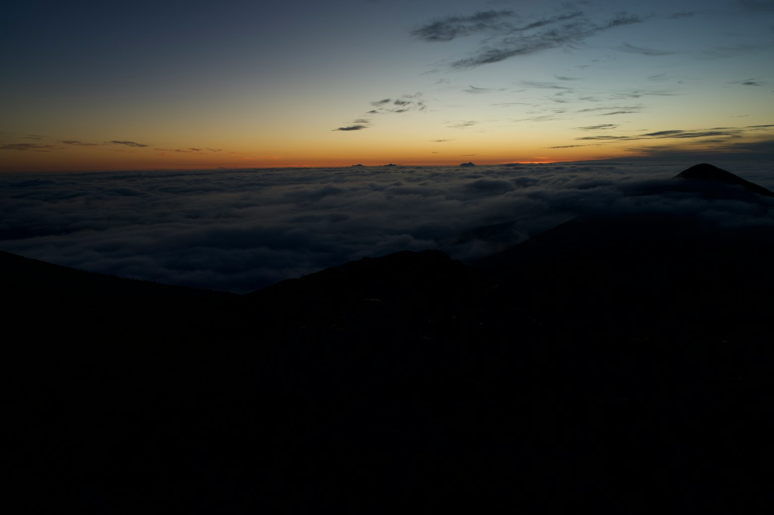 Silhouette de montagnes avec coucher de soleil sur une mer de nuages