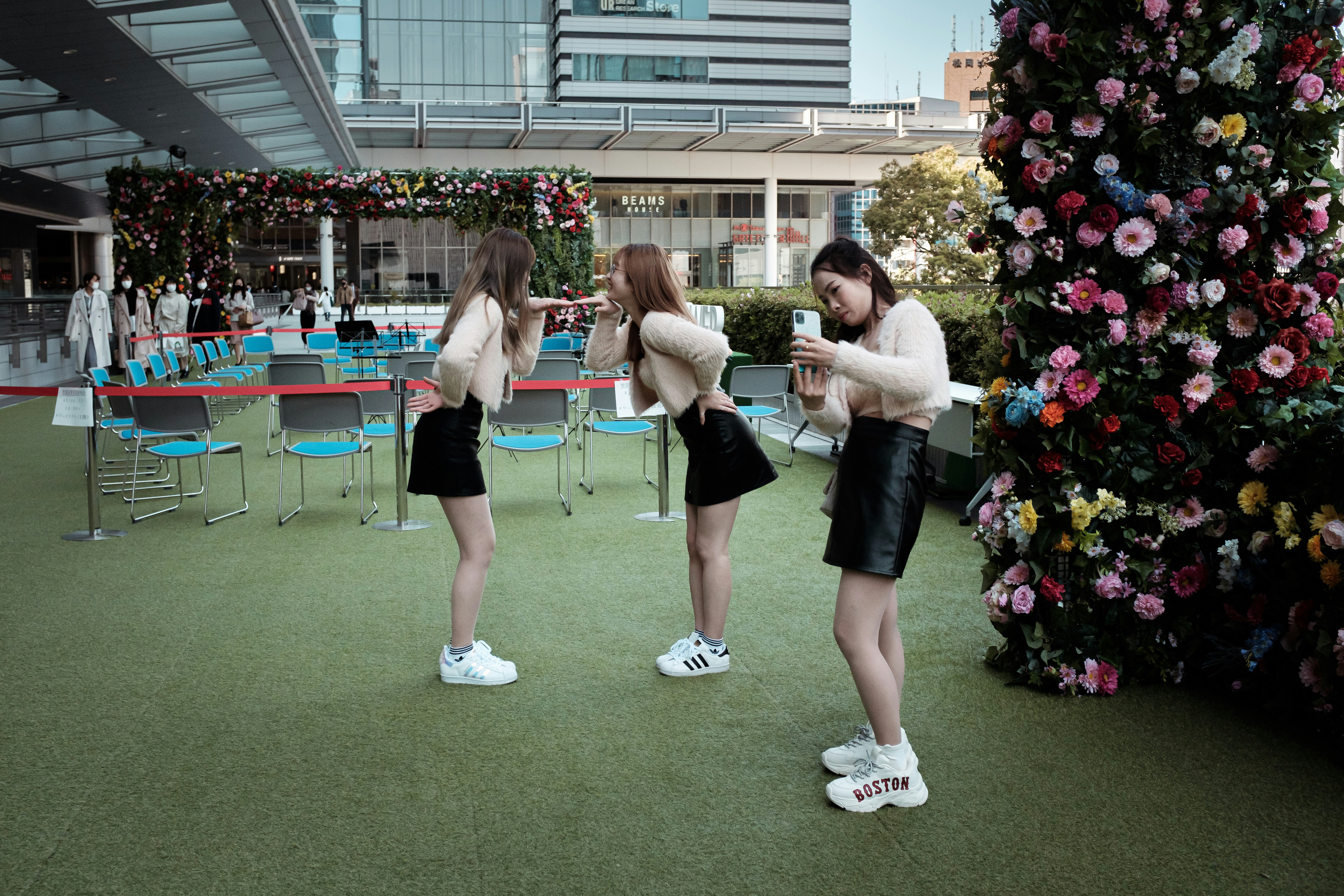 야외 잔디 공간에서 꽃 벽 앞에 선 사람들