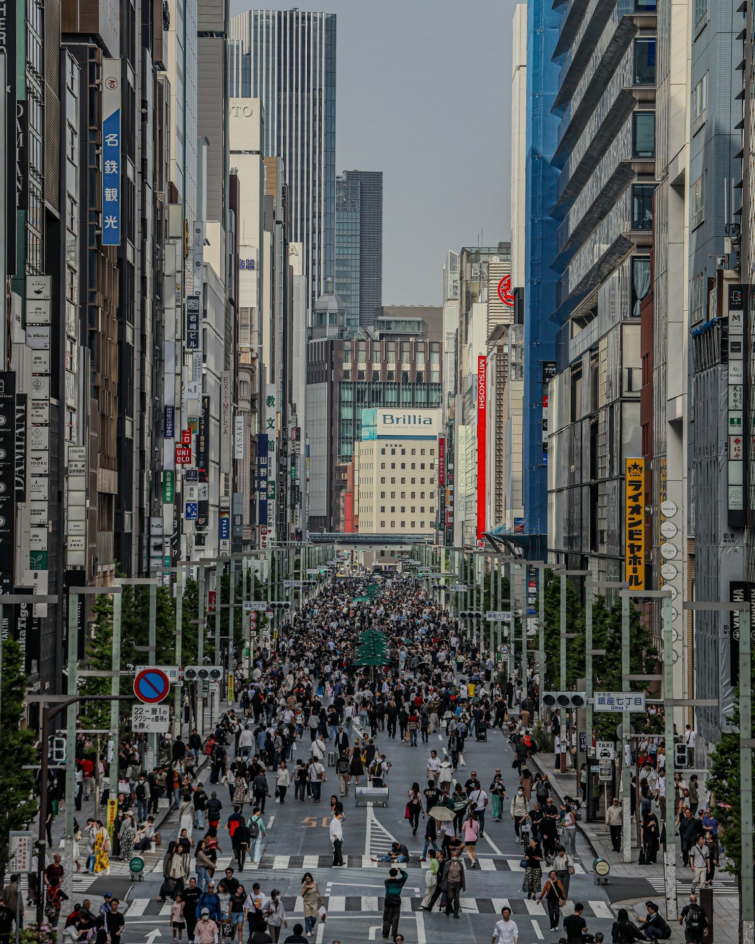 Menschenmenge in einer belebten Straße in Tokio mit hohen Gebäuden