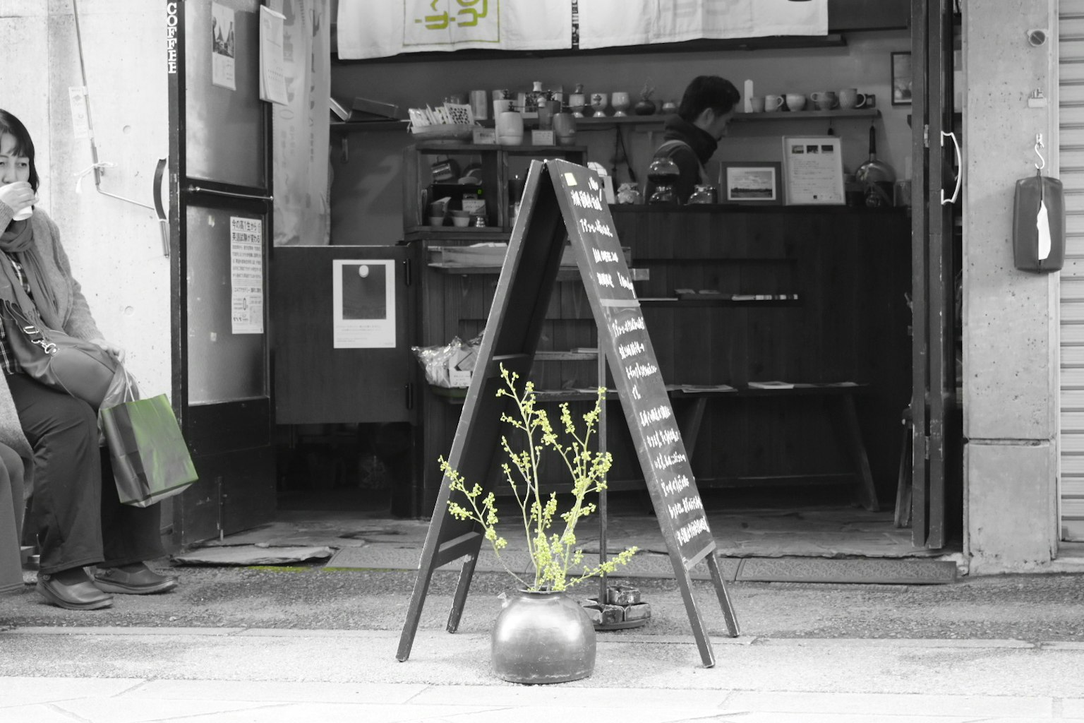 ร้านค้าที่มีป้ายเมนูและต้นไม้ในกระถางในโทนสีดำและขาว