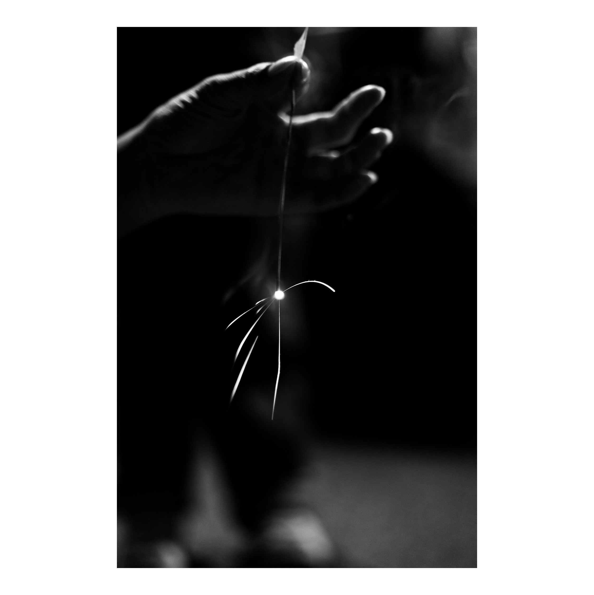 黒背景に光る火花と手のシルエット