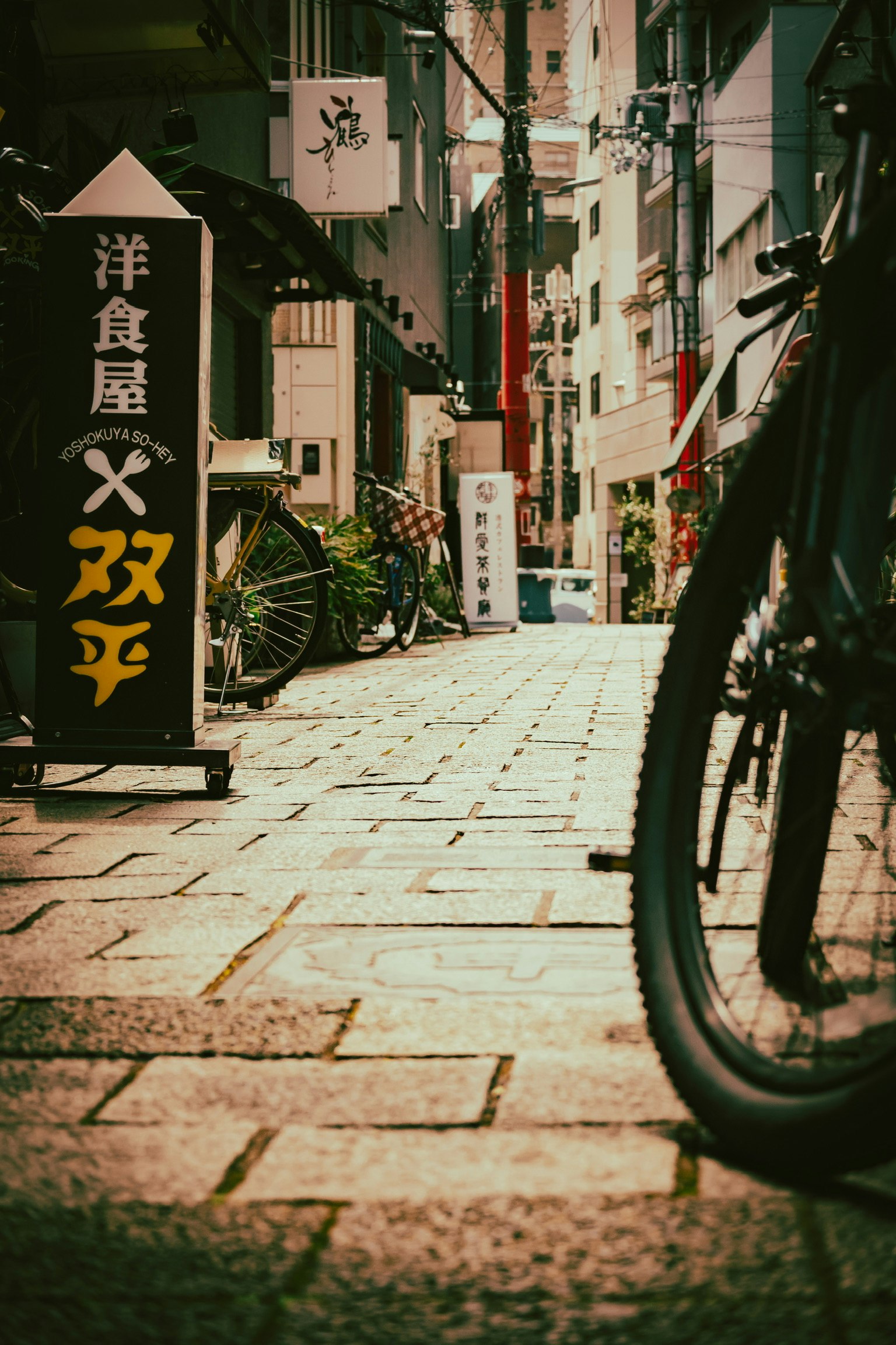 狹窄的街道上有一輛自行車和一家餐廳的招牌