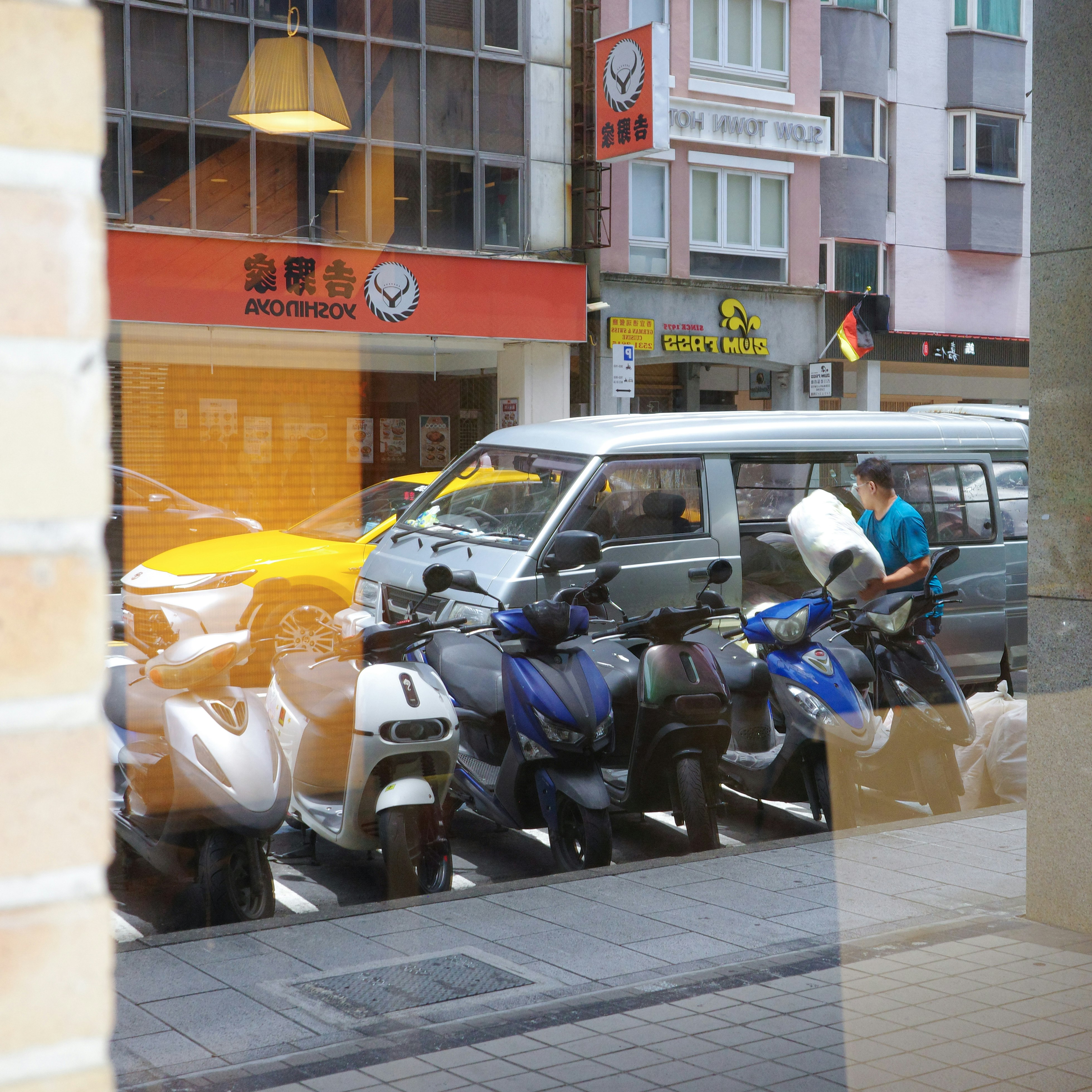 台北の街角でバイクと車が並ぶ商店街の軒先