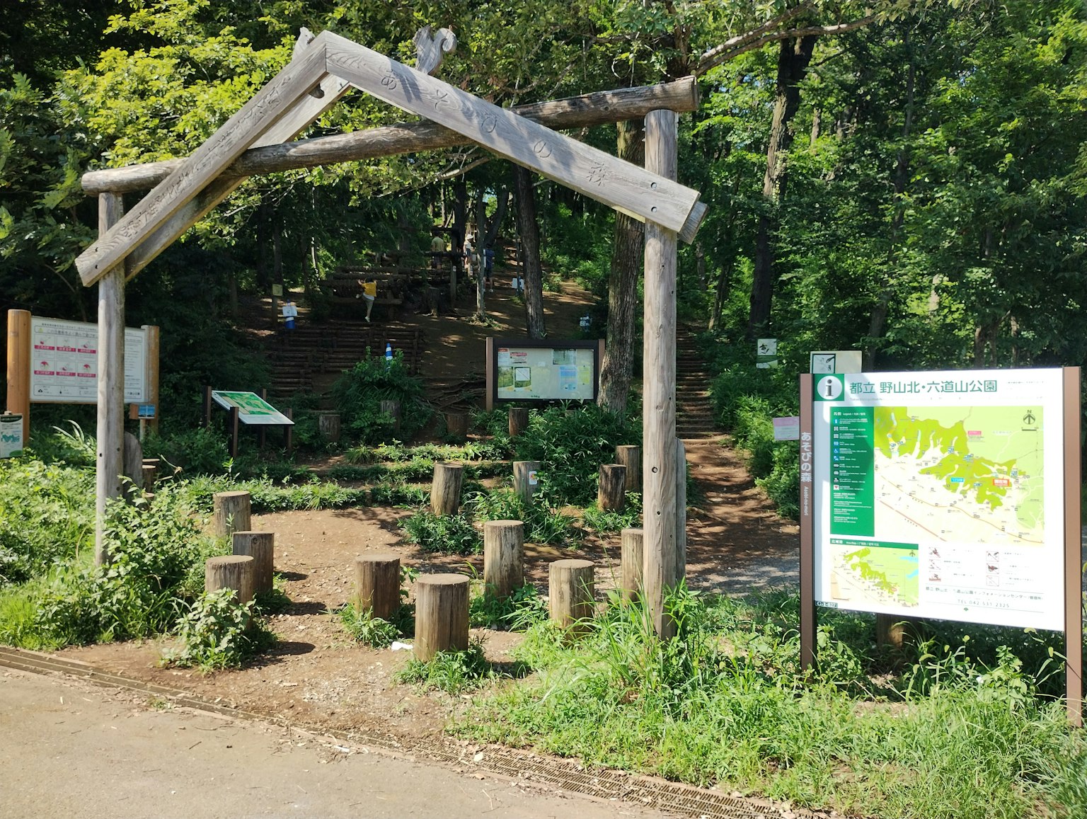 木製拱門入口通往綠意盎然的公園，帶有信息標誌