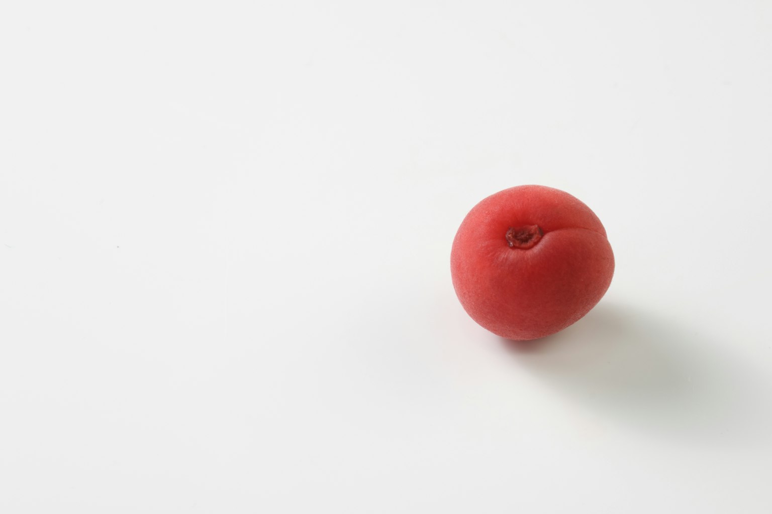 Una fruta roja sobre un fondo blanco