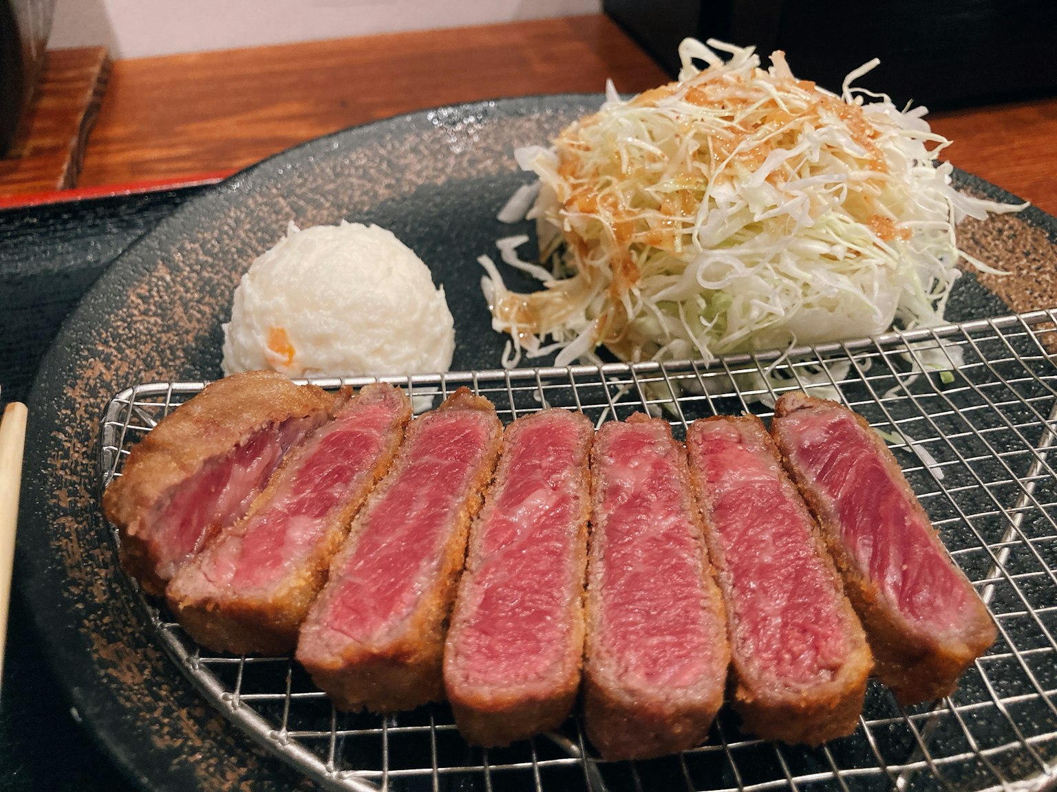 Leckere Scheiben Wagyu Katsu serviert mit Salat und Reis