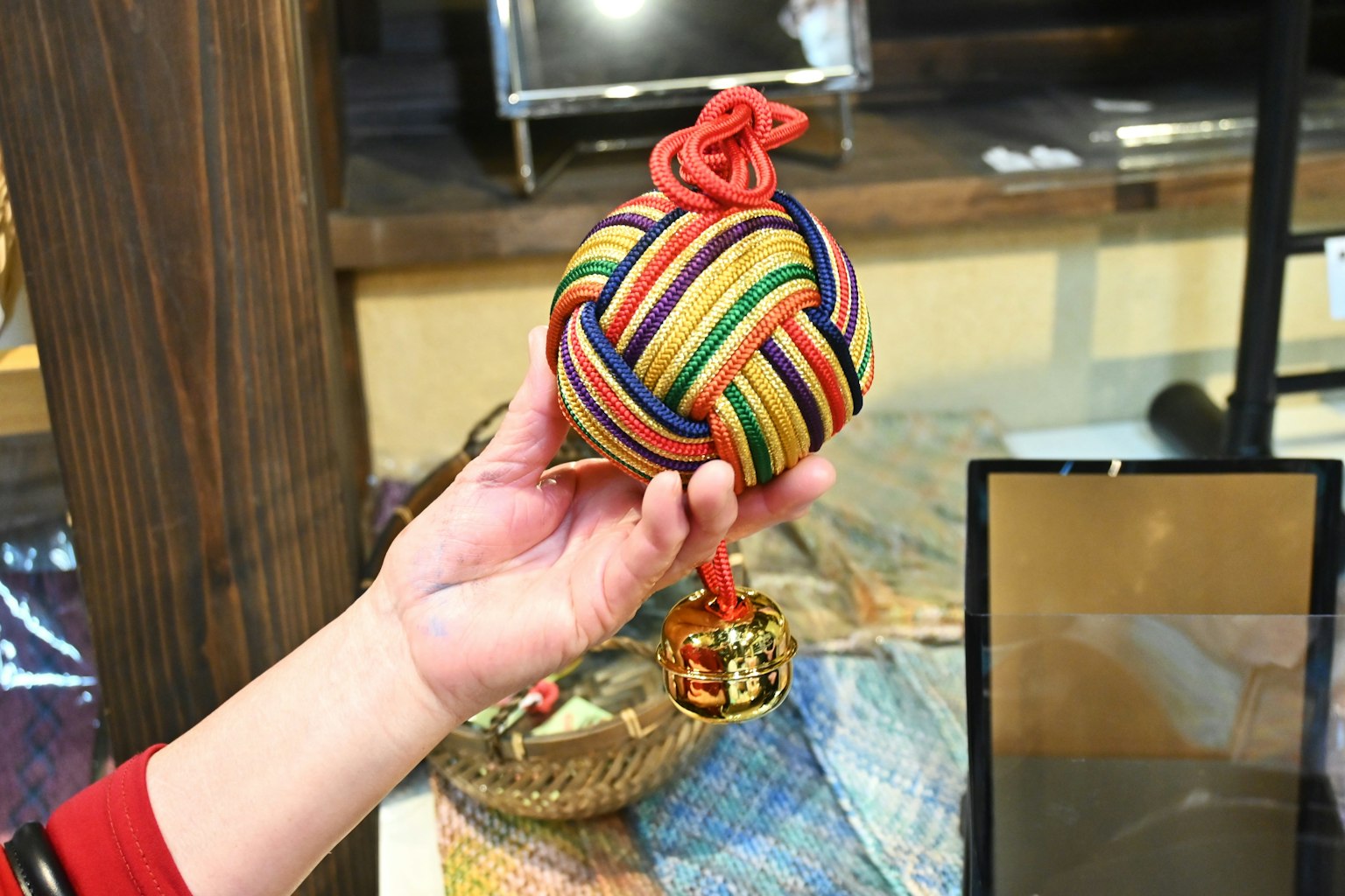 ลูกบอลดั้งเดิมที่มีสีสันถืออยู่ในมือพร้อมรายละเอียดปมสีแดง