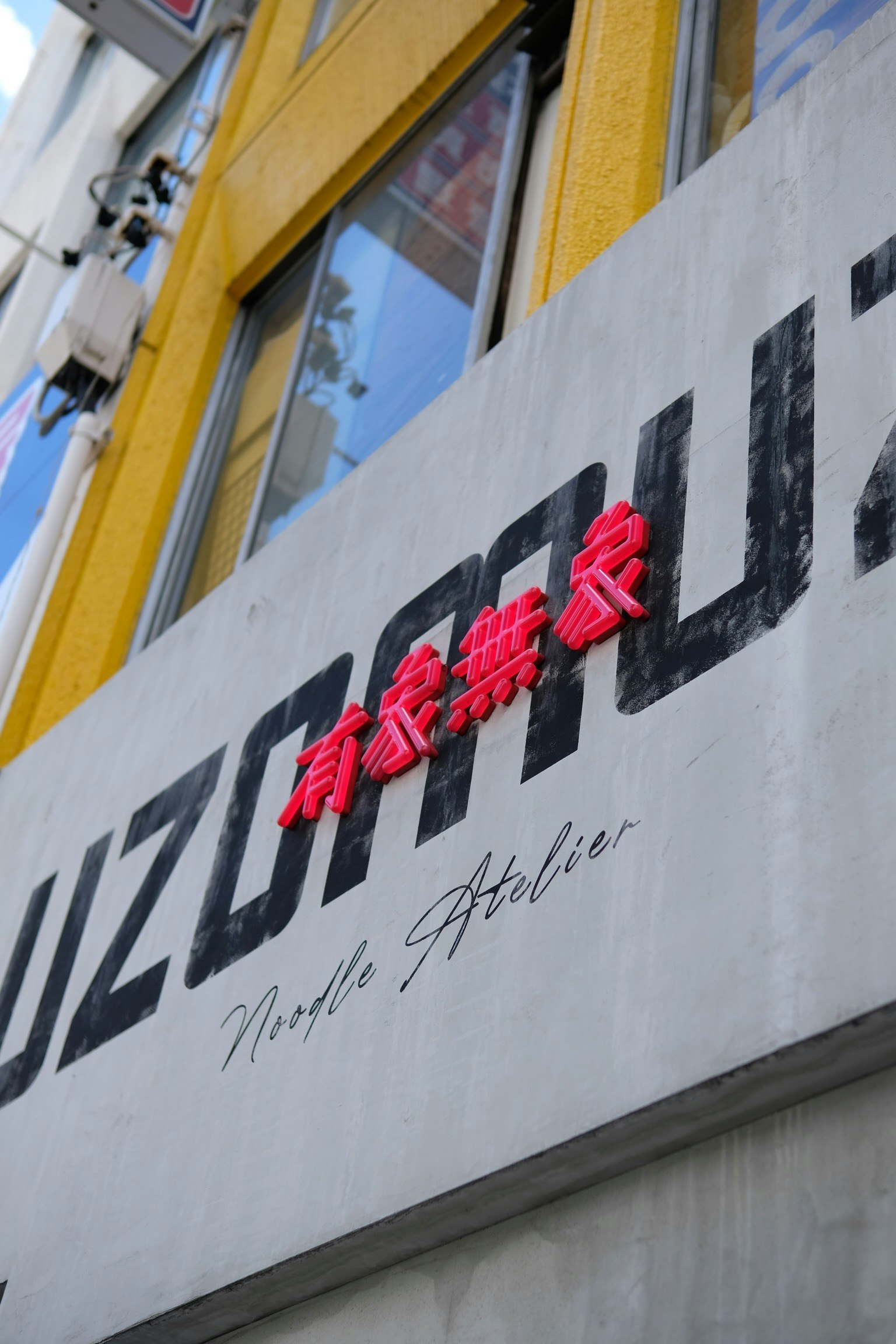 UZUMU的标志在黄色墙壁上的红色字母