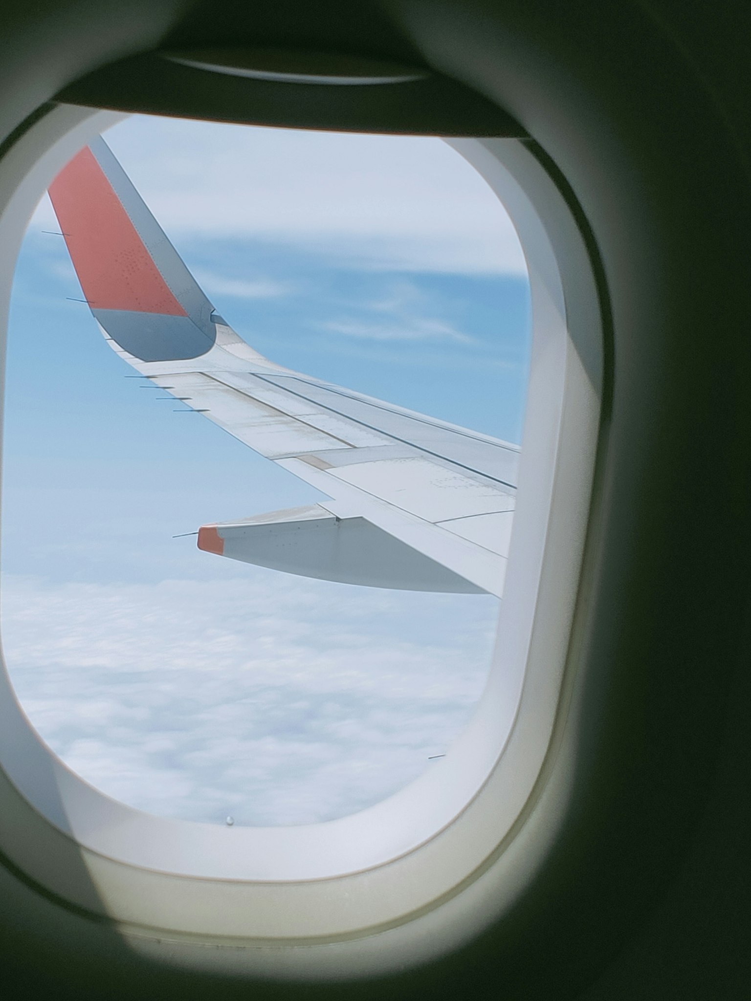 Blick auf den Flugzeugflügel und den blauen Himmel vom Fenster aus