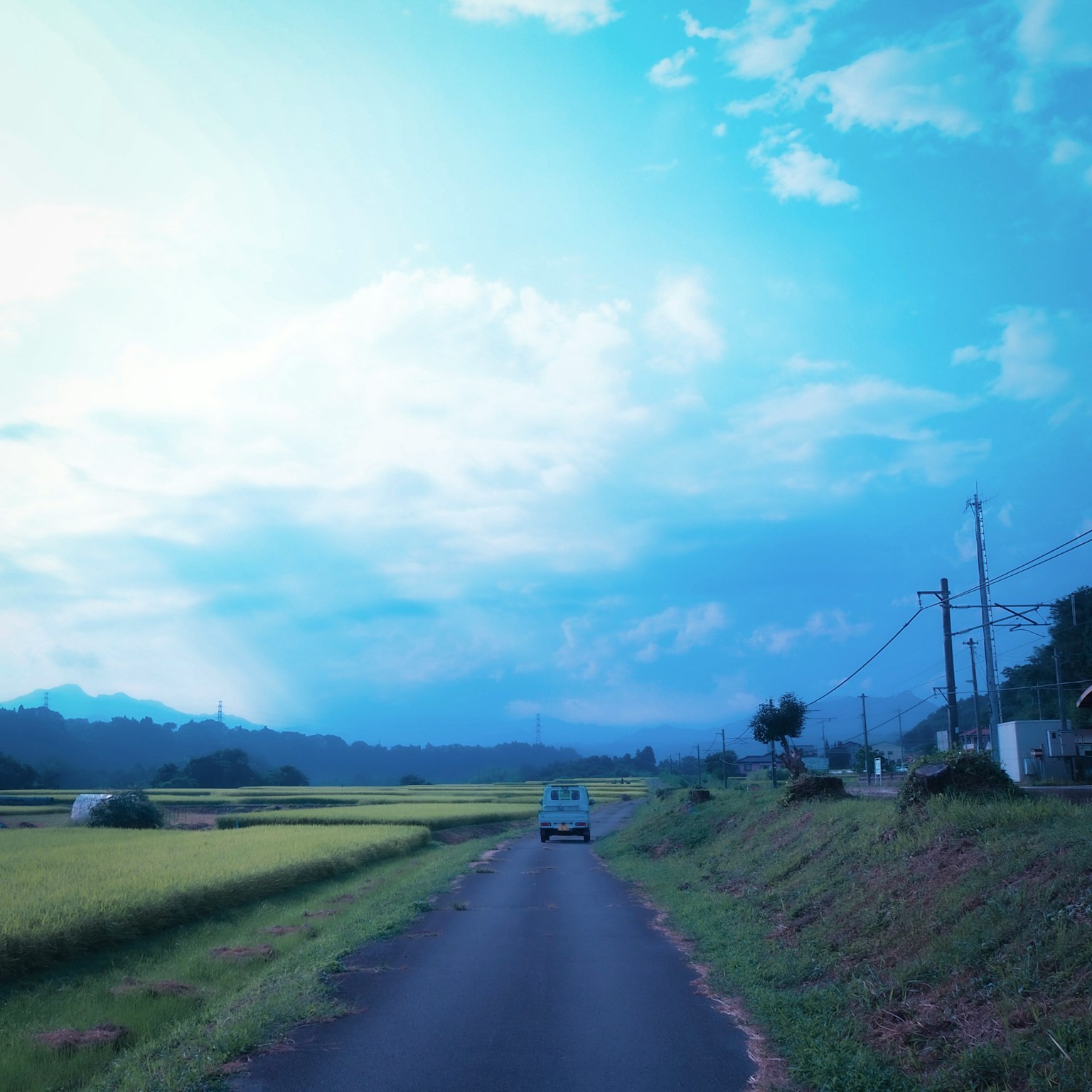 Jalan pedesaan dengan sawah di bawah langit biru mobil yang melaju