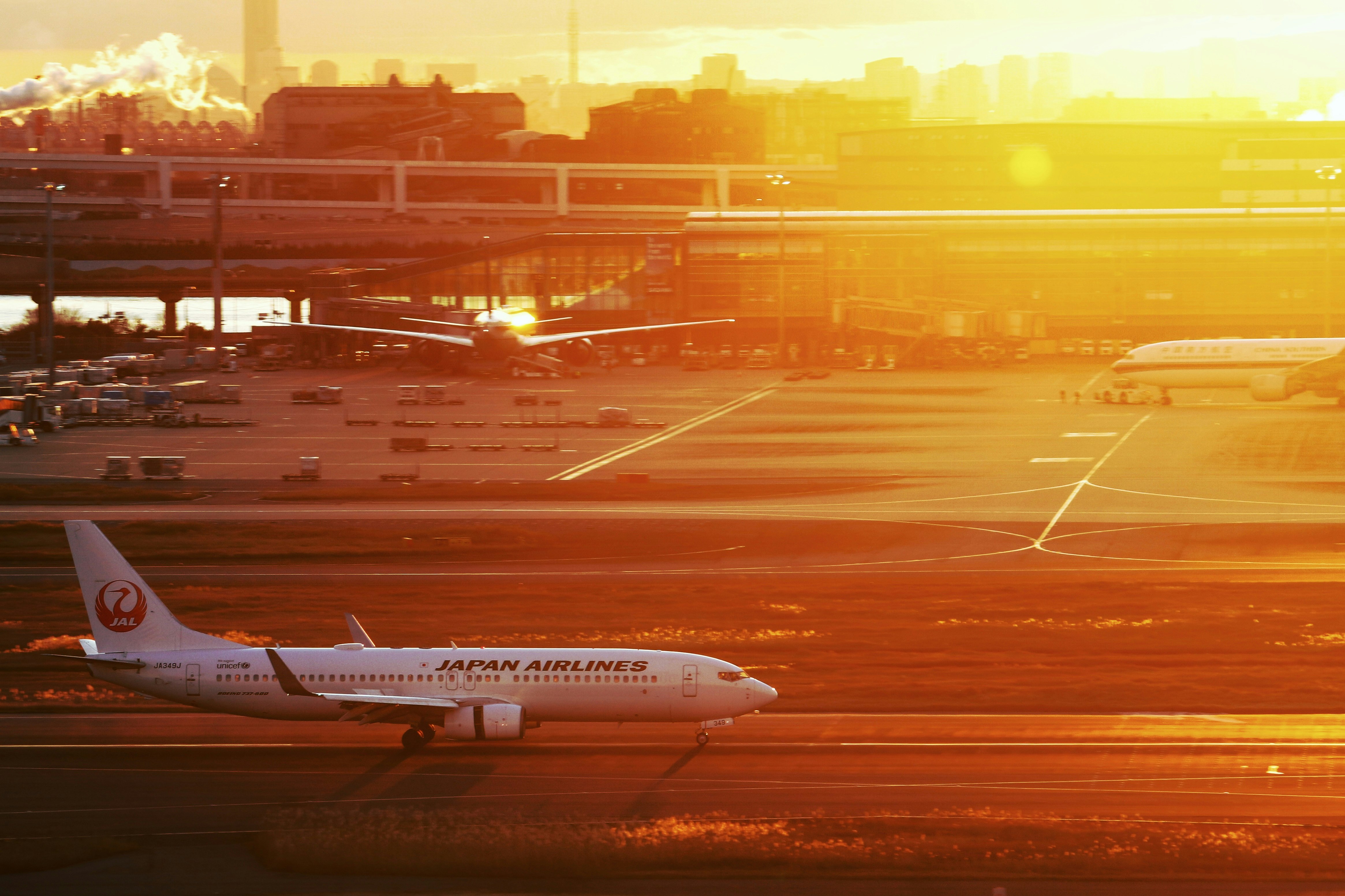 夕日に照らされた滑走路と駐機中の旅客機のある空港の風景