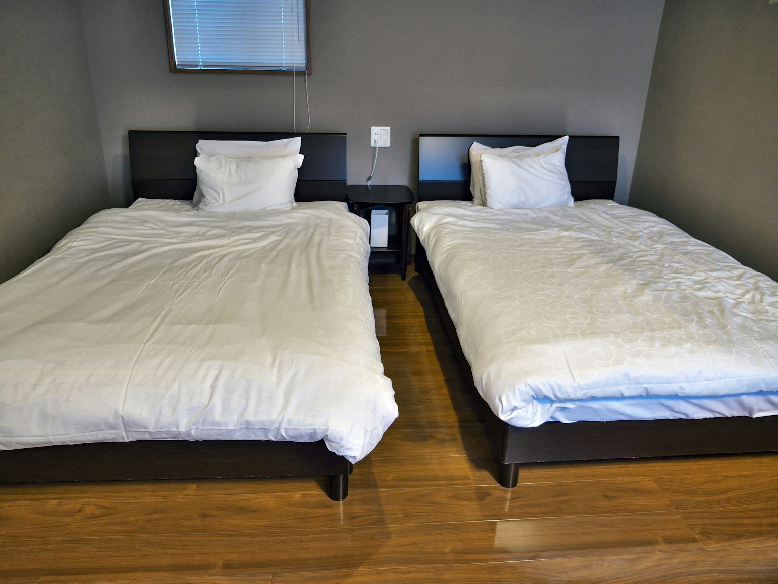 Dormitorio simple con dos camas individuales y sábanas blancas