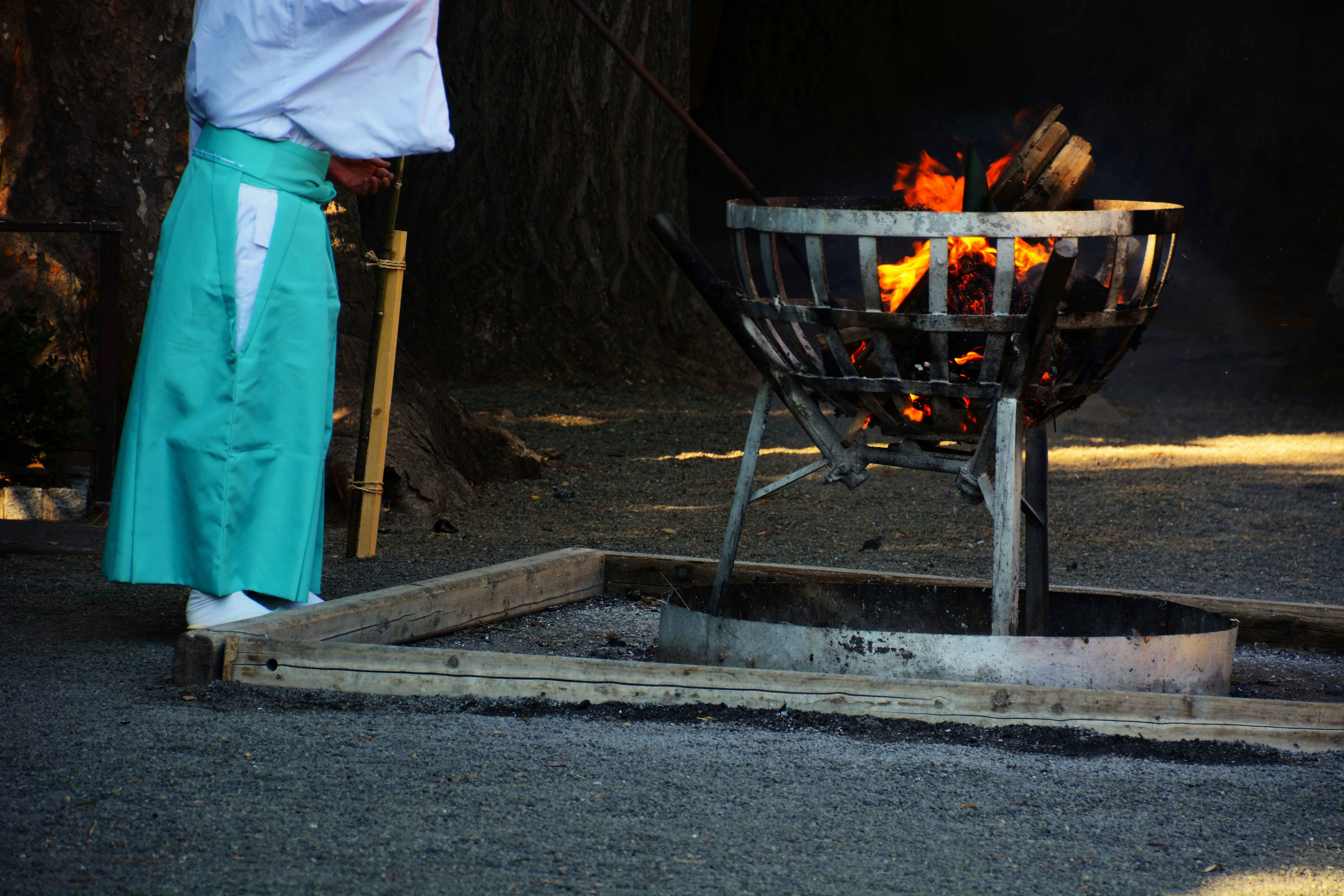 Shinto shrine grounds with a priest beside a campfire