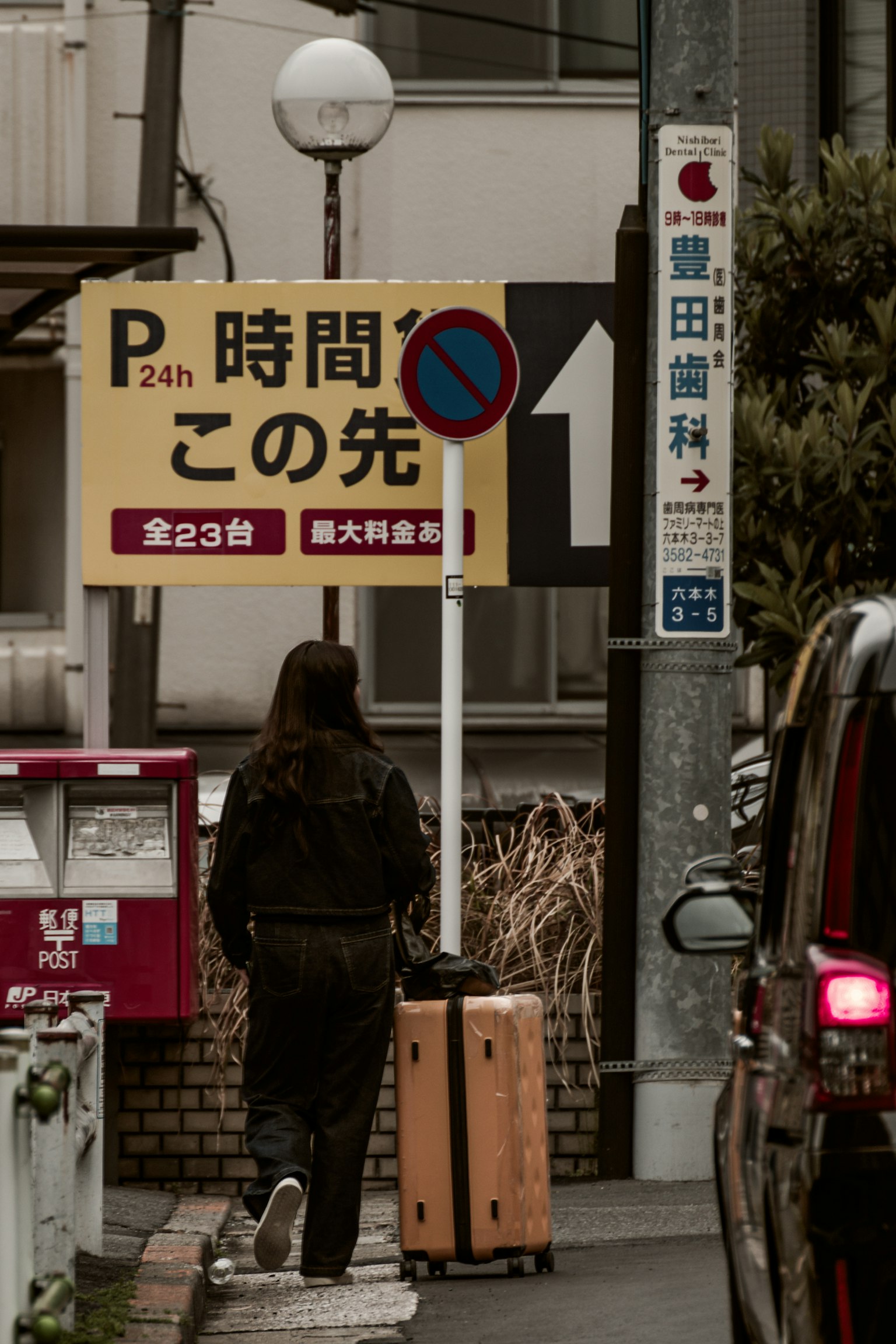 주차 표지판과 캐리어를 들고 걷는 사람의 거리 풍경