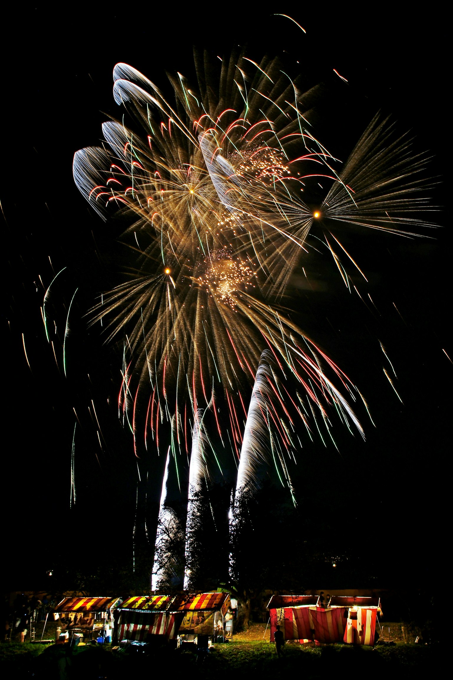 Colorful fireworks bursting in the night sky with illuminated stalls in the foreground